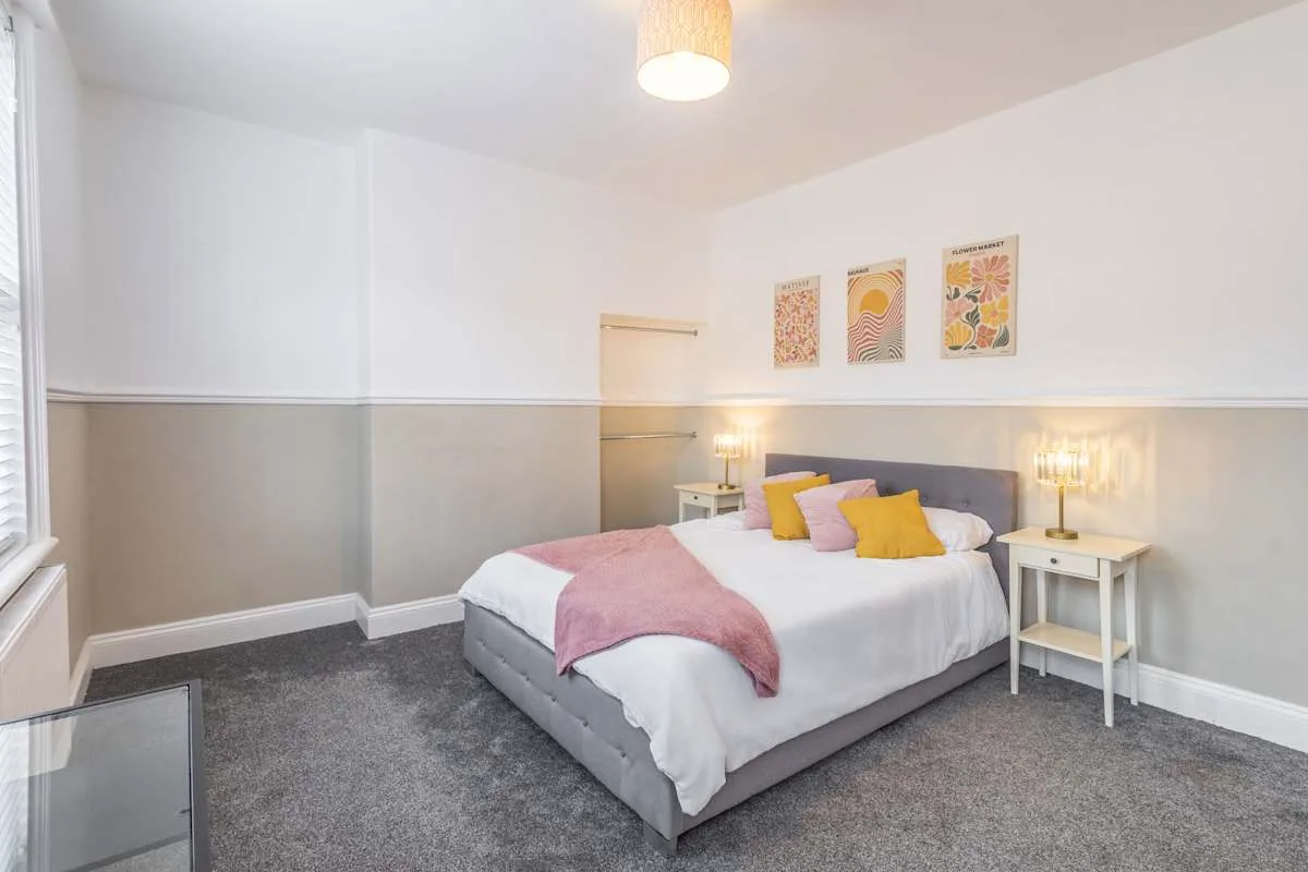 Un dormitorio con una cama, mesitas de noche y cuadros en la pared.