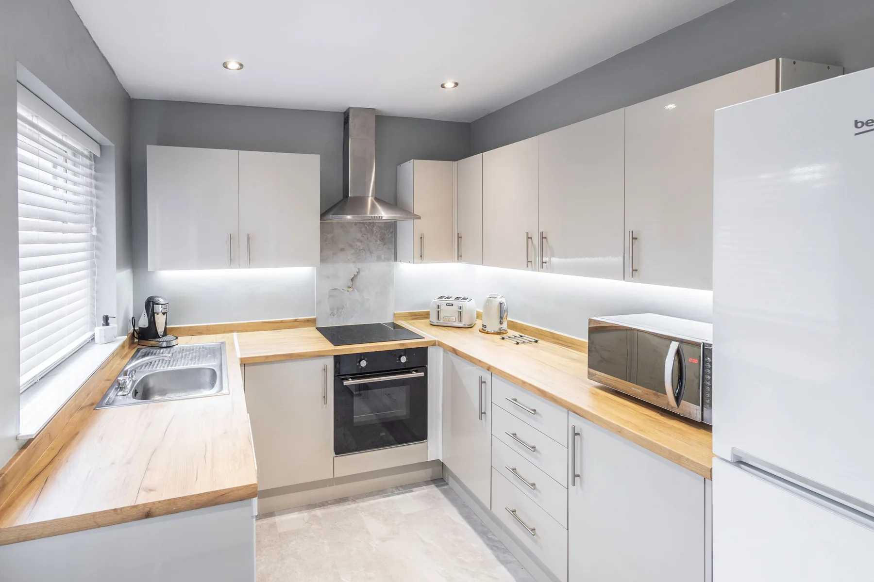 A bright kitchen with white cabinets, wooden countertops, and stainless steel appliances.
