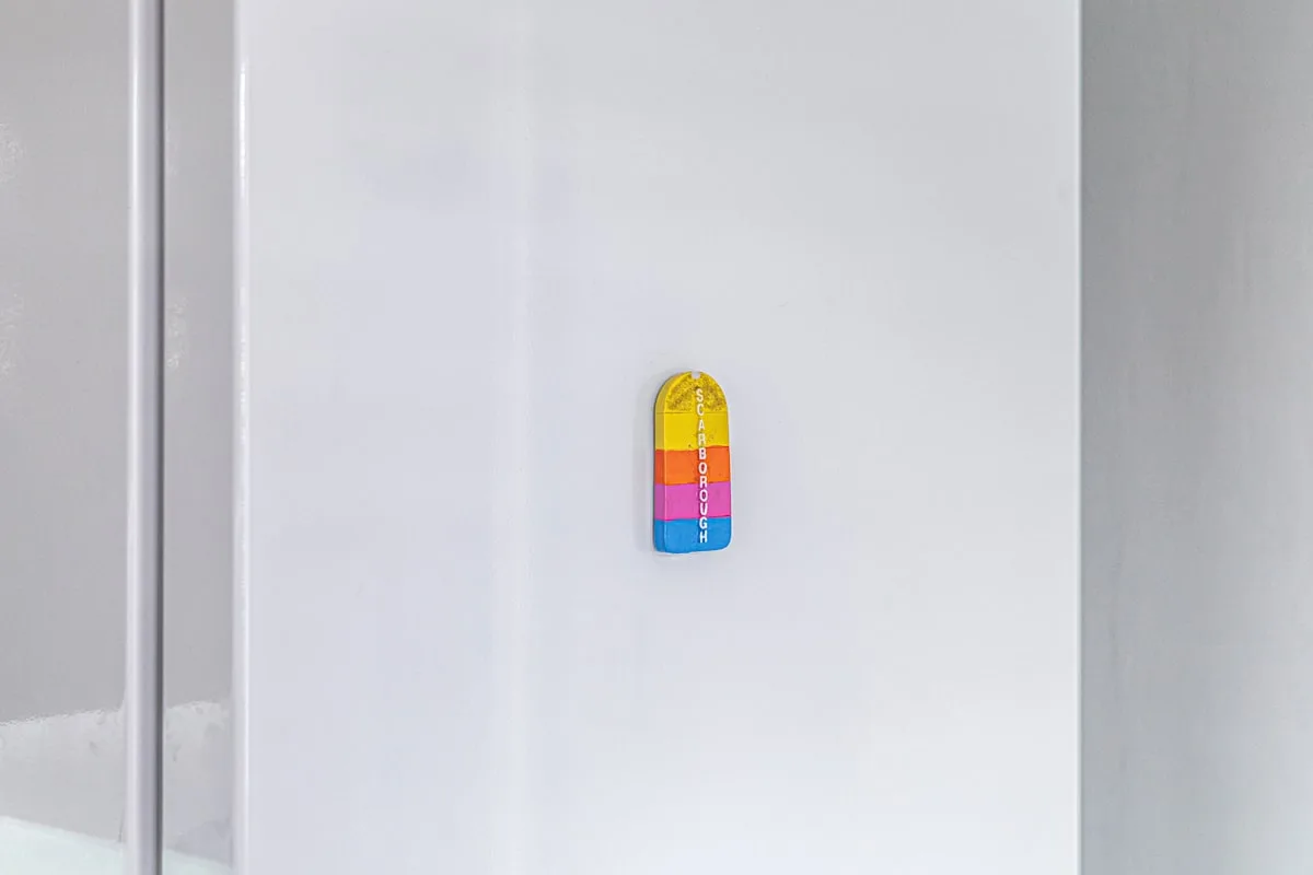 Un pequeño adorno colorido está colocado en una pared blanca.