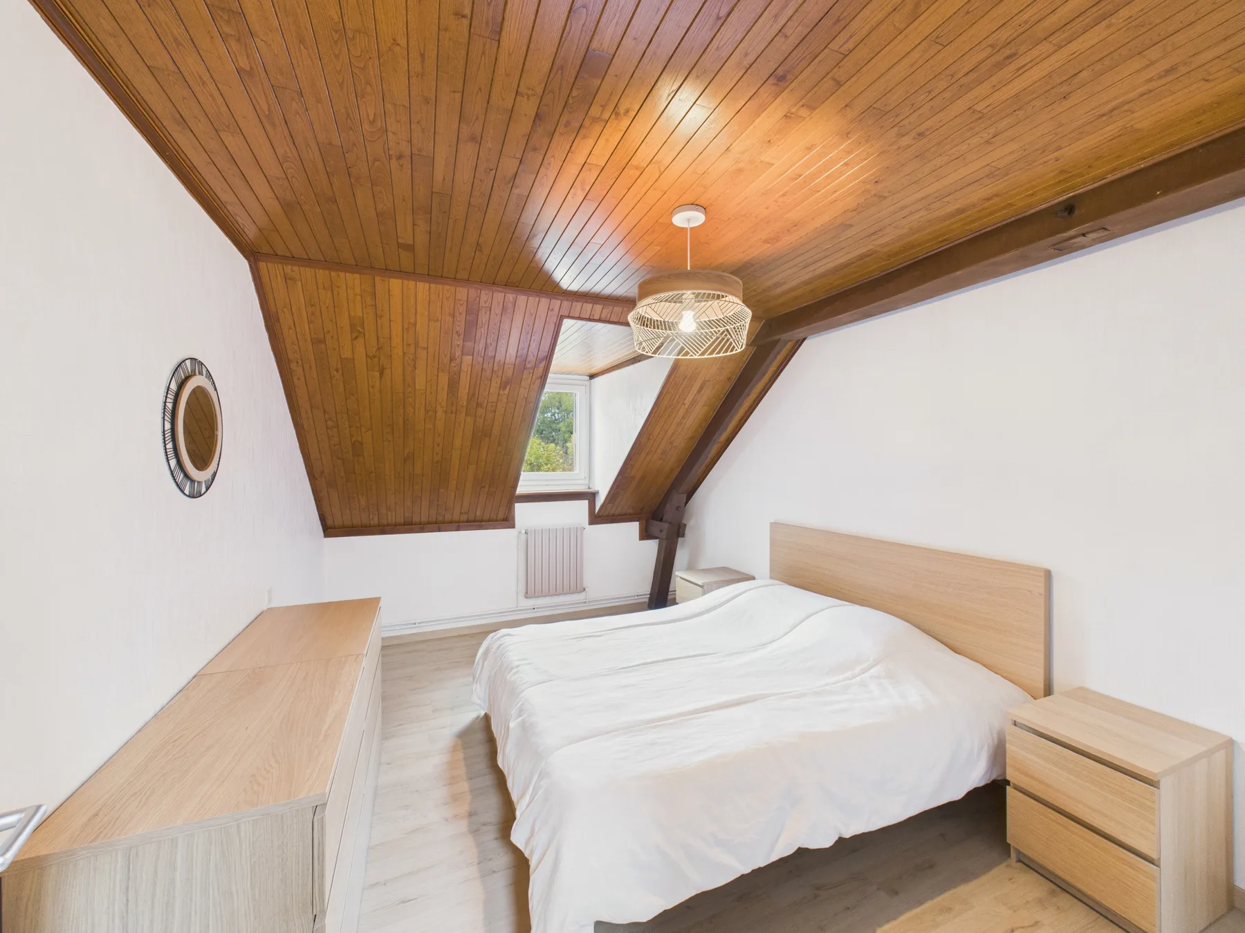 Un dormitorio con una cama bajo un techo inclinado de madera.