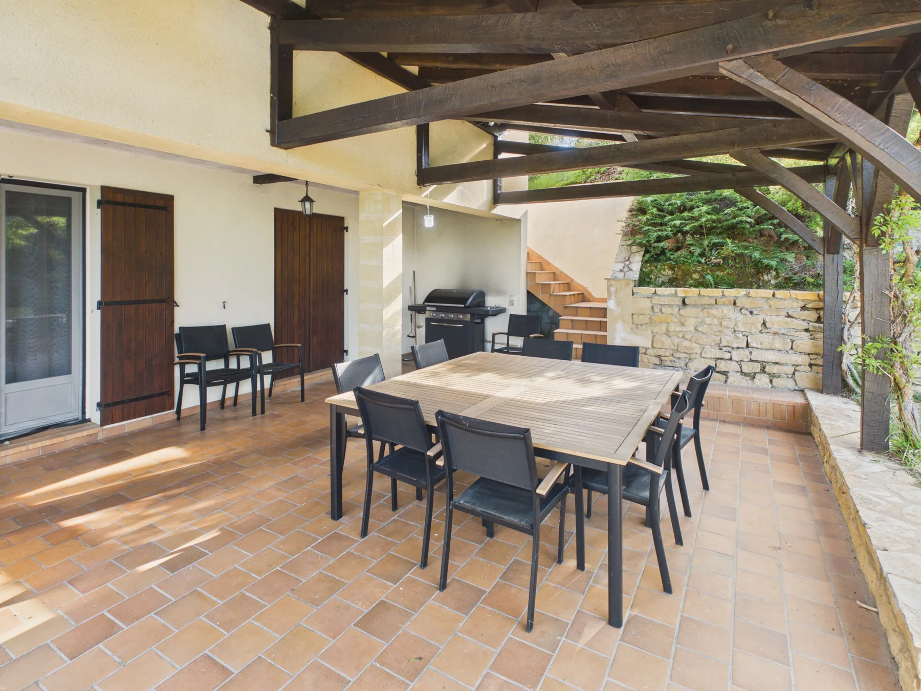 Comedor exterior cubierto con una mesa grande y sillas.