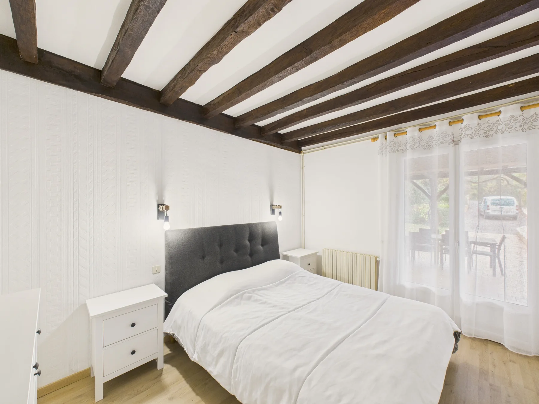 Un dormitorio con una cama doble bajo vigas de techo a la vista.