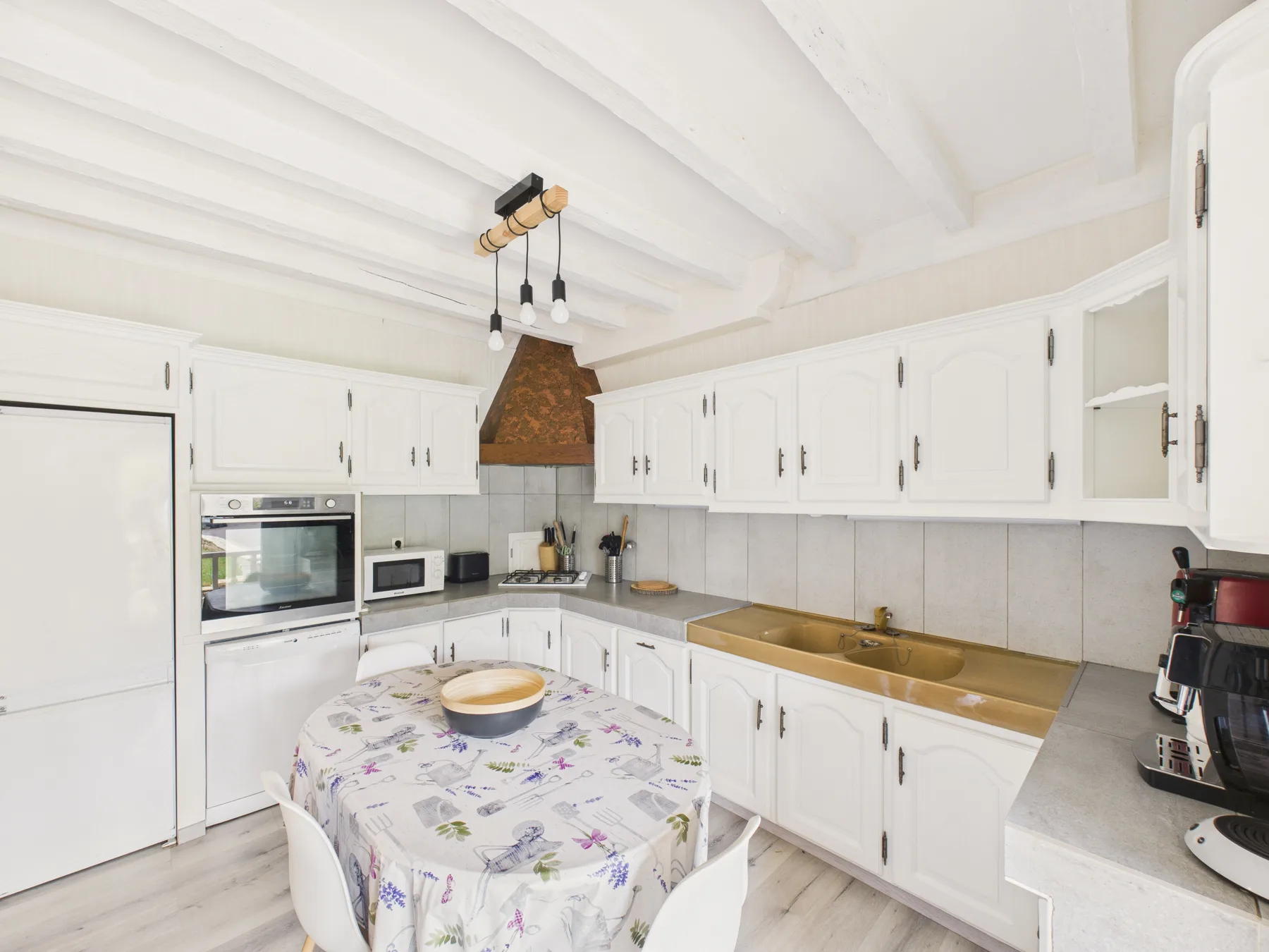 Una cocina blanca y luminosa con una mesa redonda y una encimera larga.