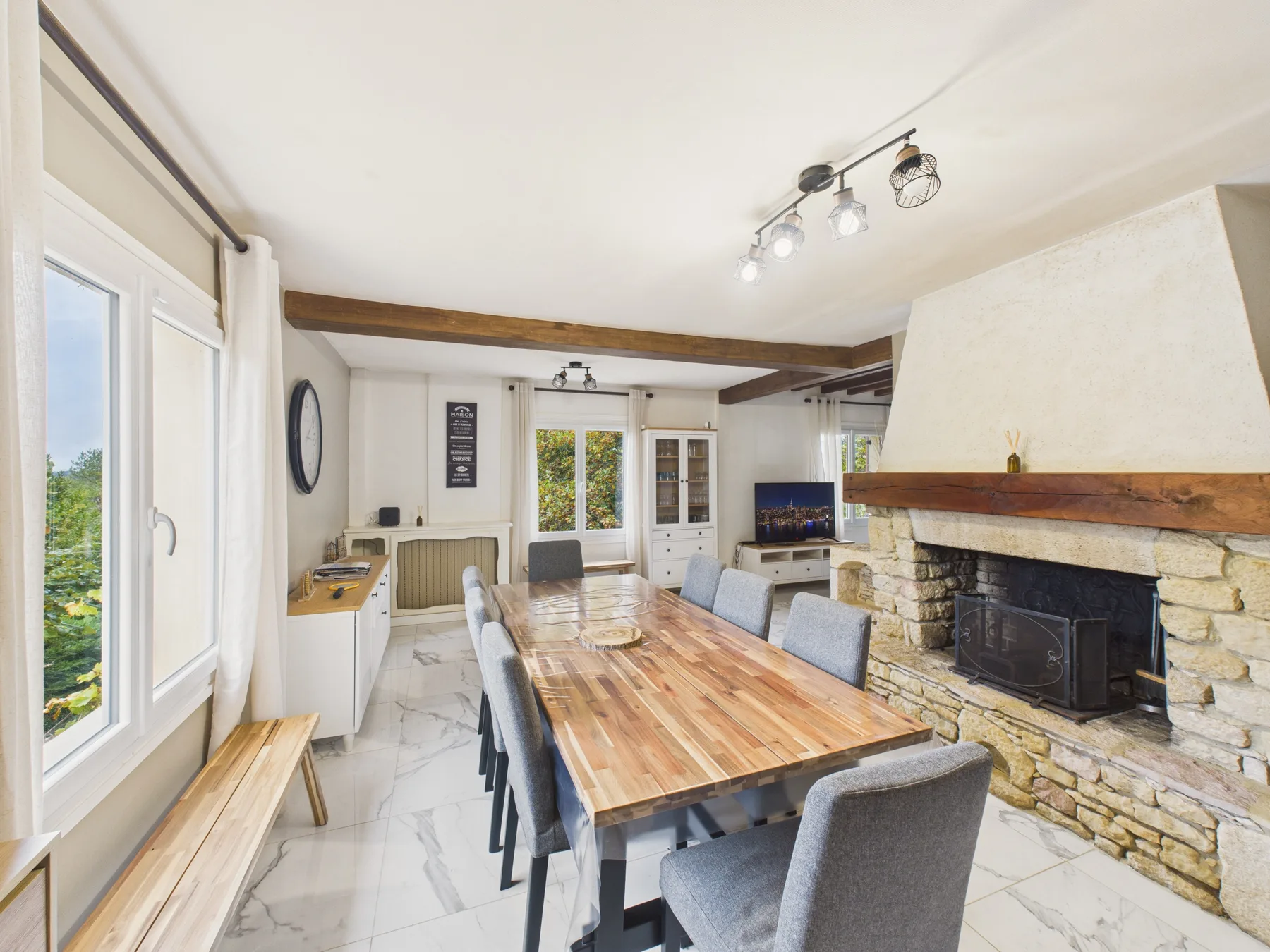 Comedor con una larga mesa de madera junto a una chimenea de piedra.