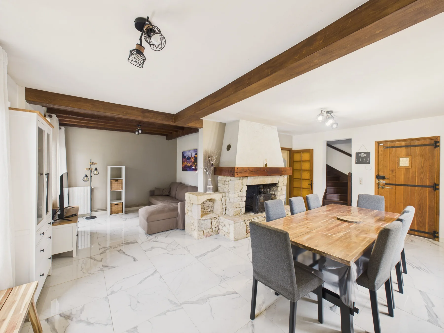 Sala y comedor de concepto abierto con chimenea de piedra y mesa de madera.