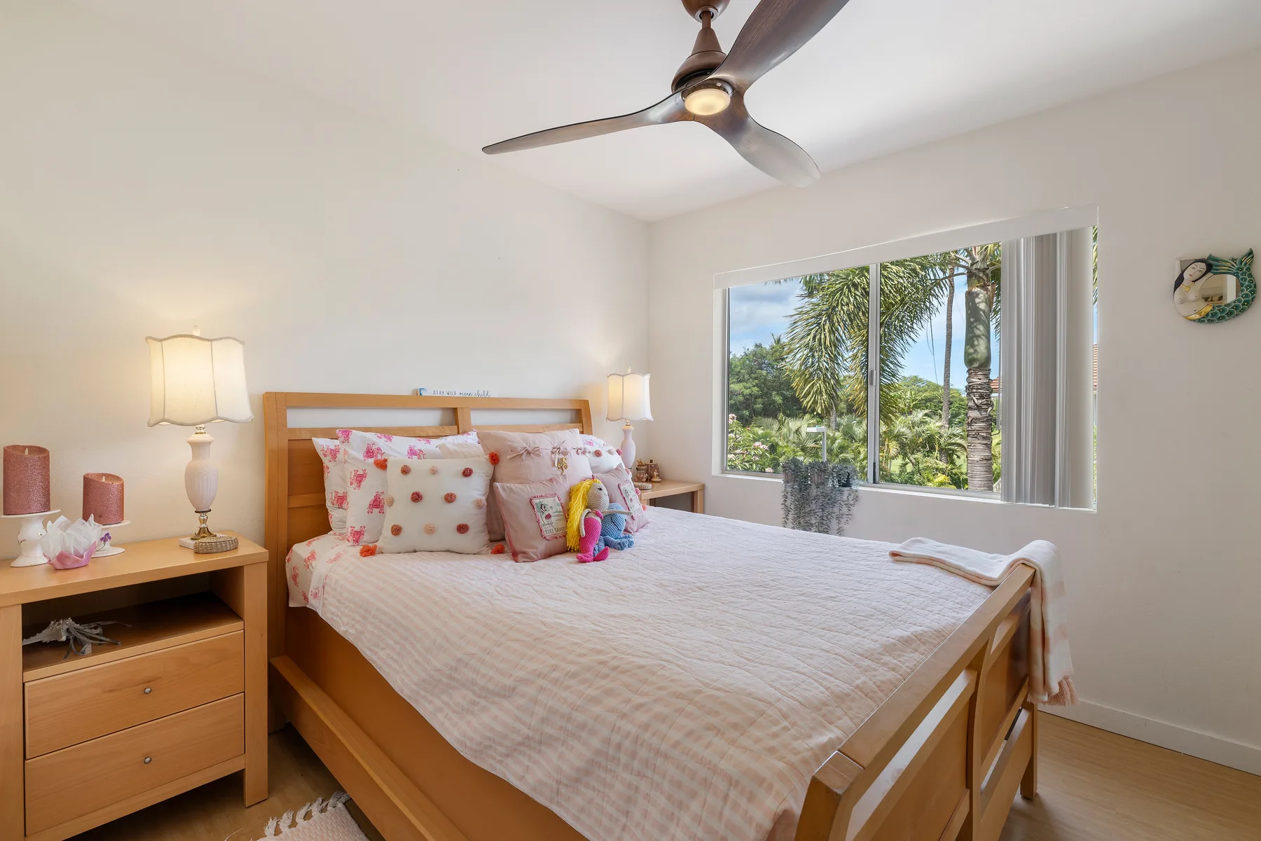 A bedroom with a wooden bed and a large window overlooking greenery.