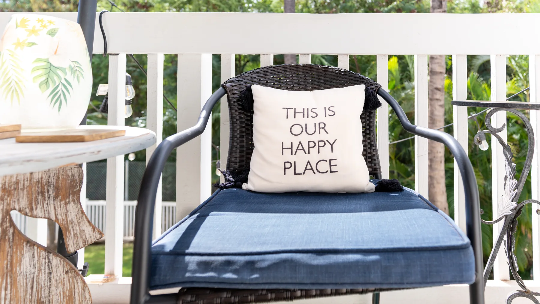 A cushioned chair sits on a porch beside a small round table.