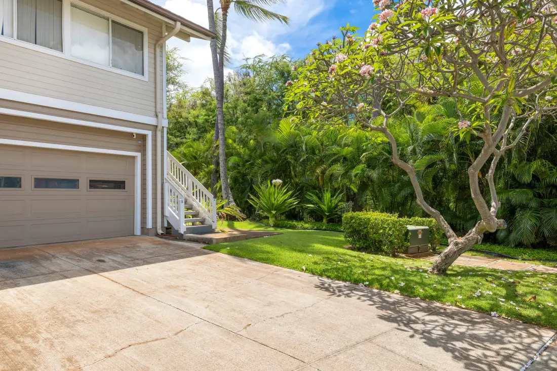 A house exterior with a driveway, garage, and landscaped garden.