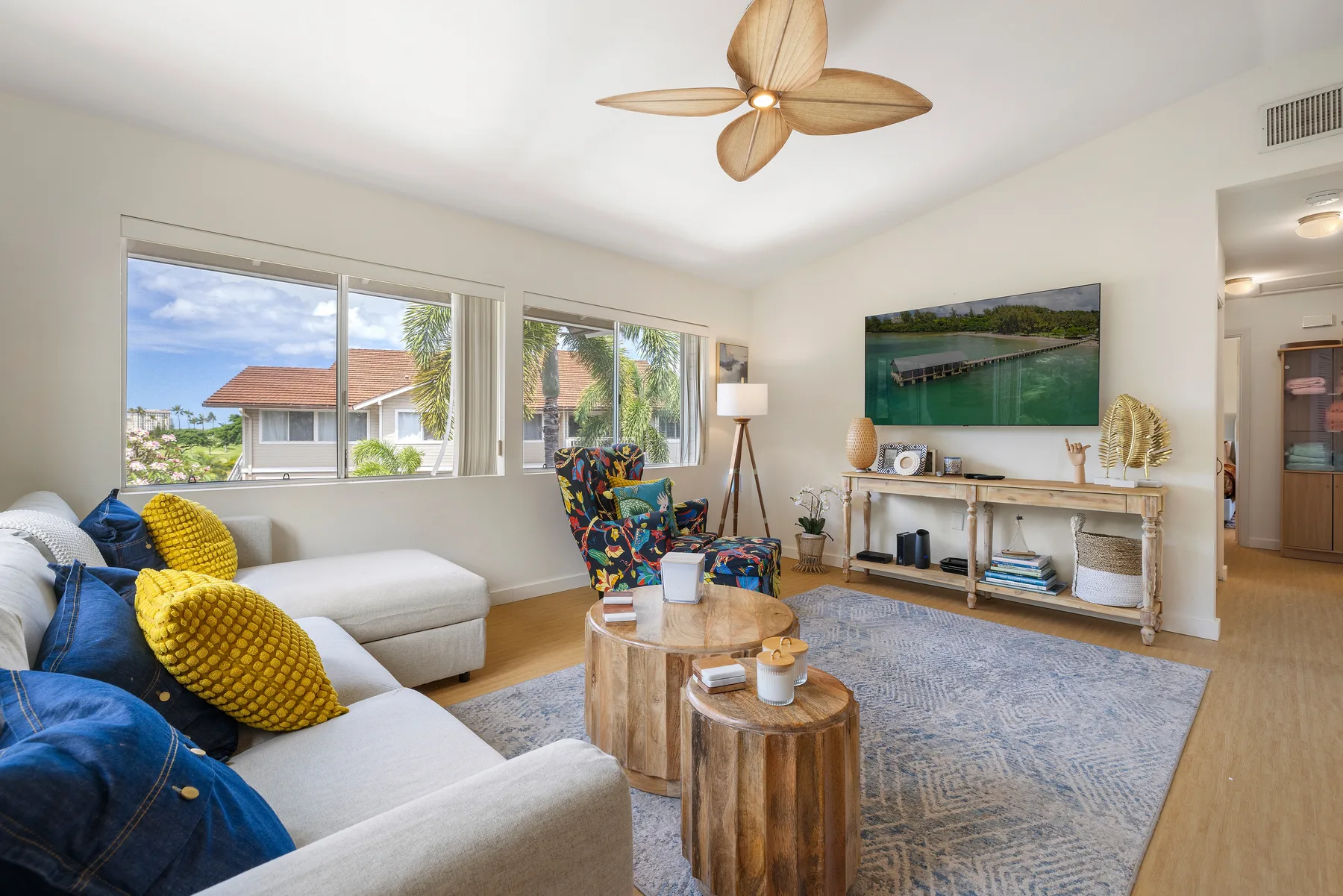 A bright living room with seating, a coffee table, and large windows.