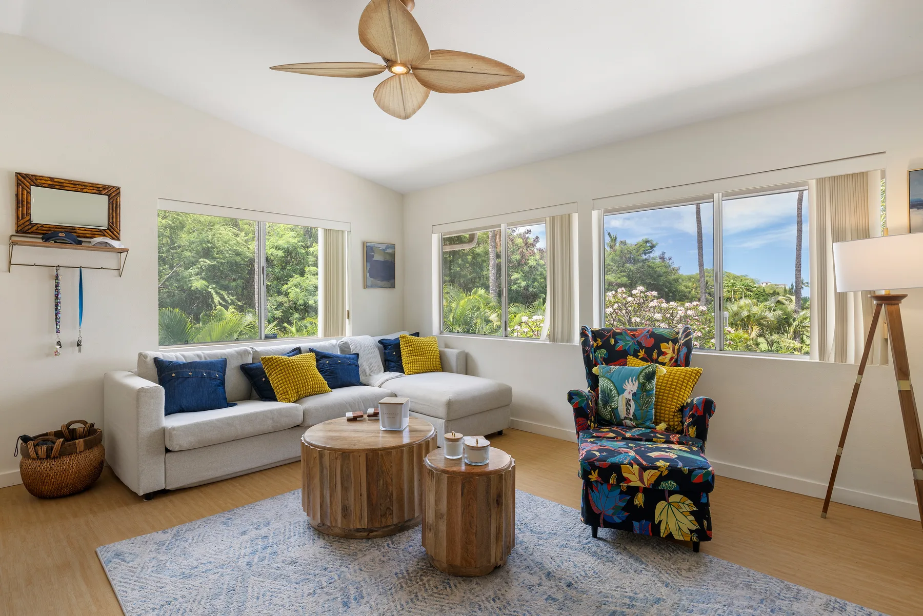 A bright living room with a sectional sofa, colorful chair, and large windows.