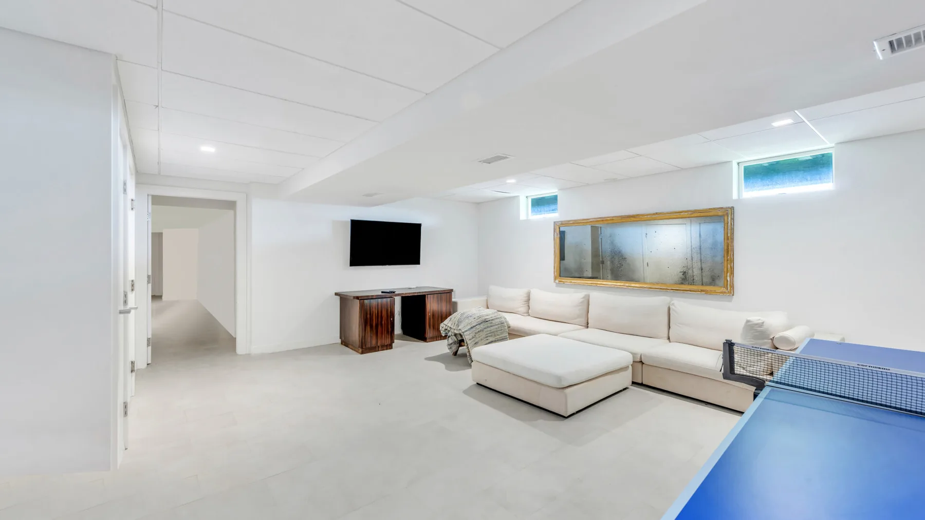 A bright basement living room with a sectional sofa and a television.