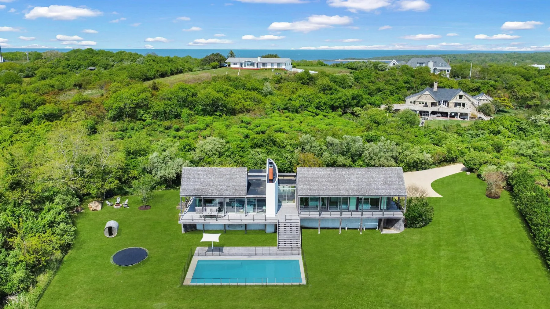 Aerial view of a modern house with a swimming pool amid green grounds.