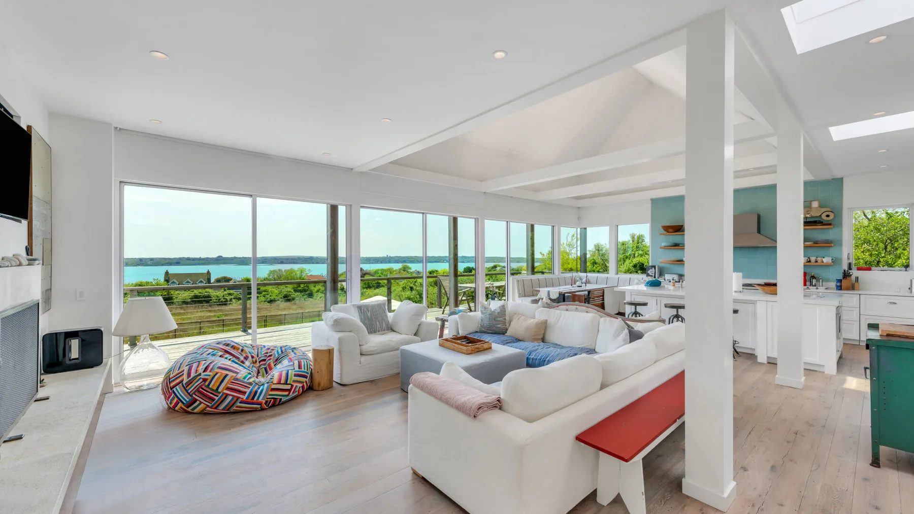A bright living room with seating beside large windows overlooking the water.