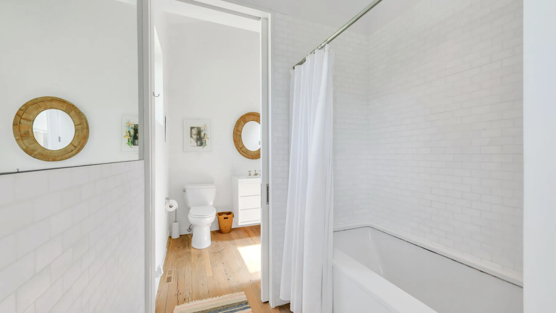 A bright bathroom with a bathtub behind a white shower curtain.