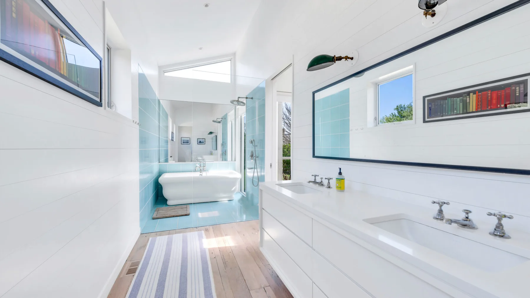 A bright bathroom with a bathtub, glass shower, and long vanity.