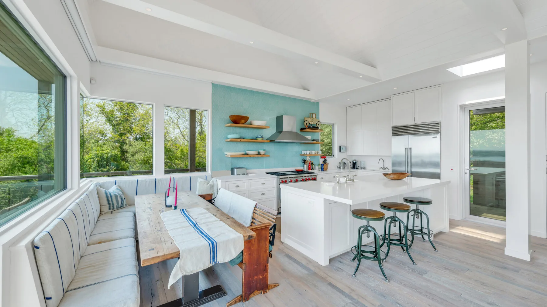 A bright open-plan kitchen and dining area with a long table and central island.