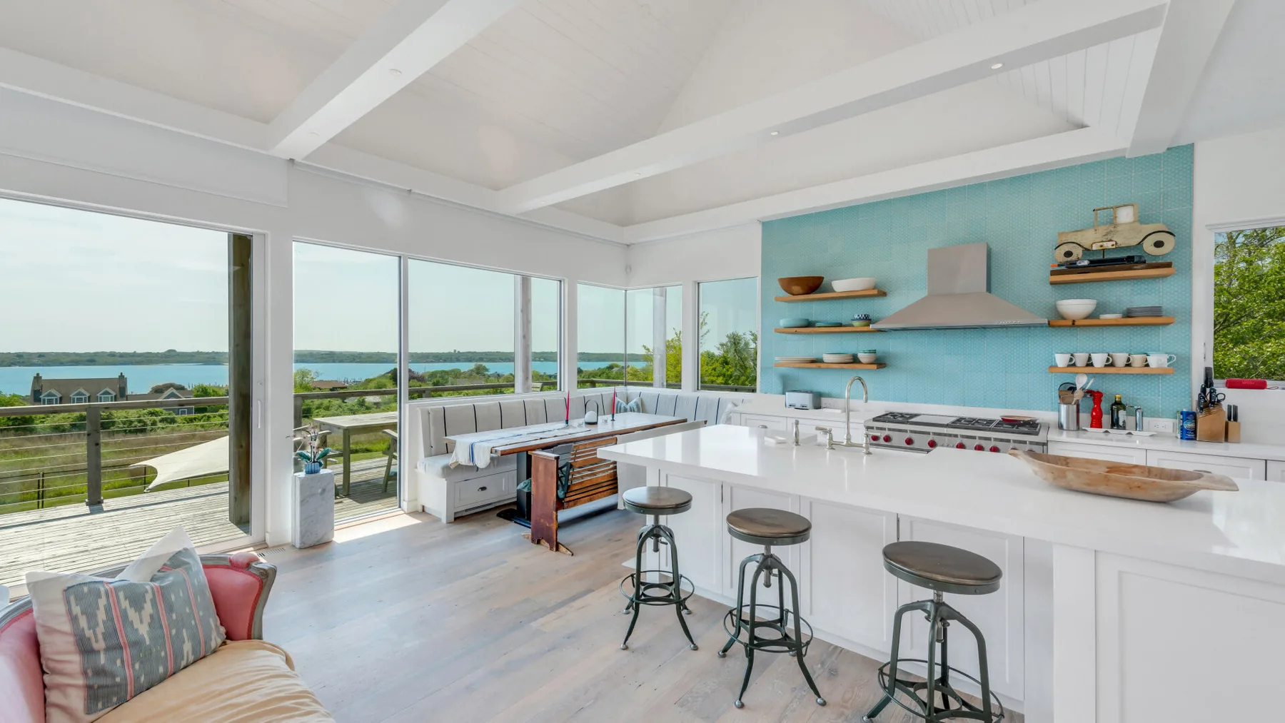 A bright kitchen with a long island and large windows overlooking the water.