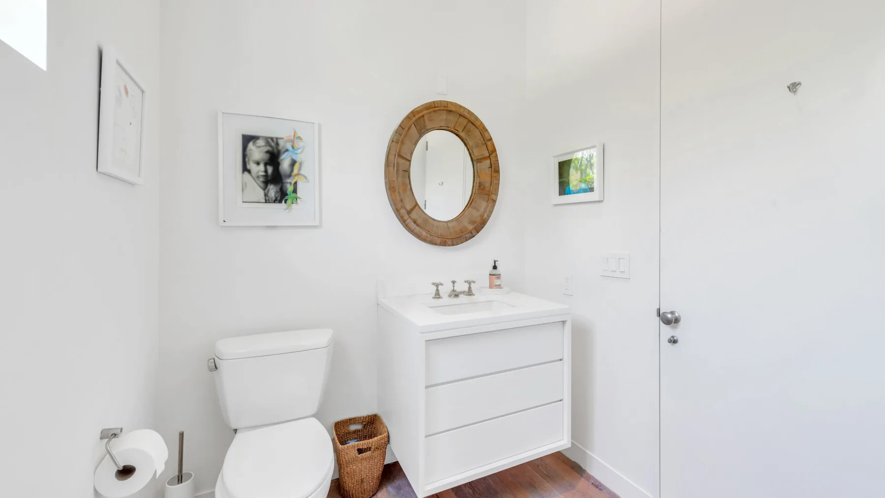 A bright bathroom with a white vanity, sink, and round wall mirror.