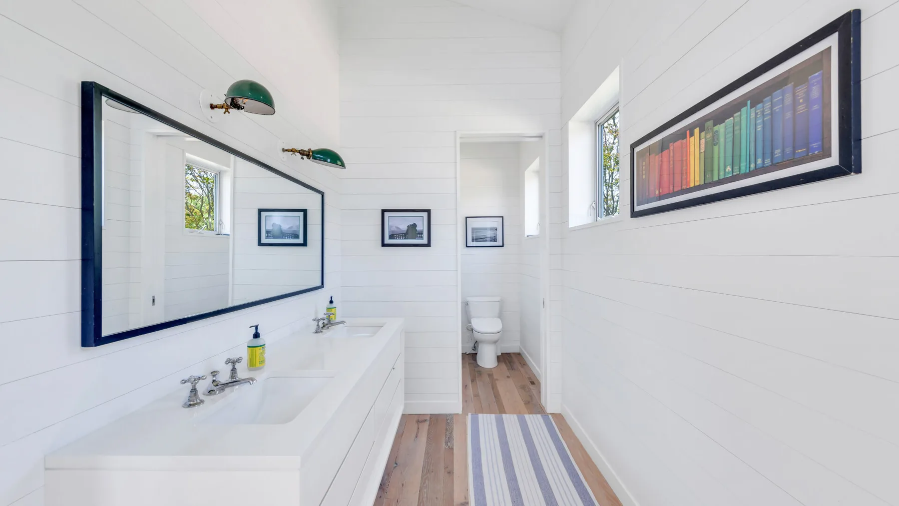 A bright bathroom with a long sink counter, wall mirror, and toilet.