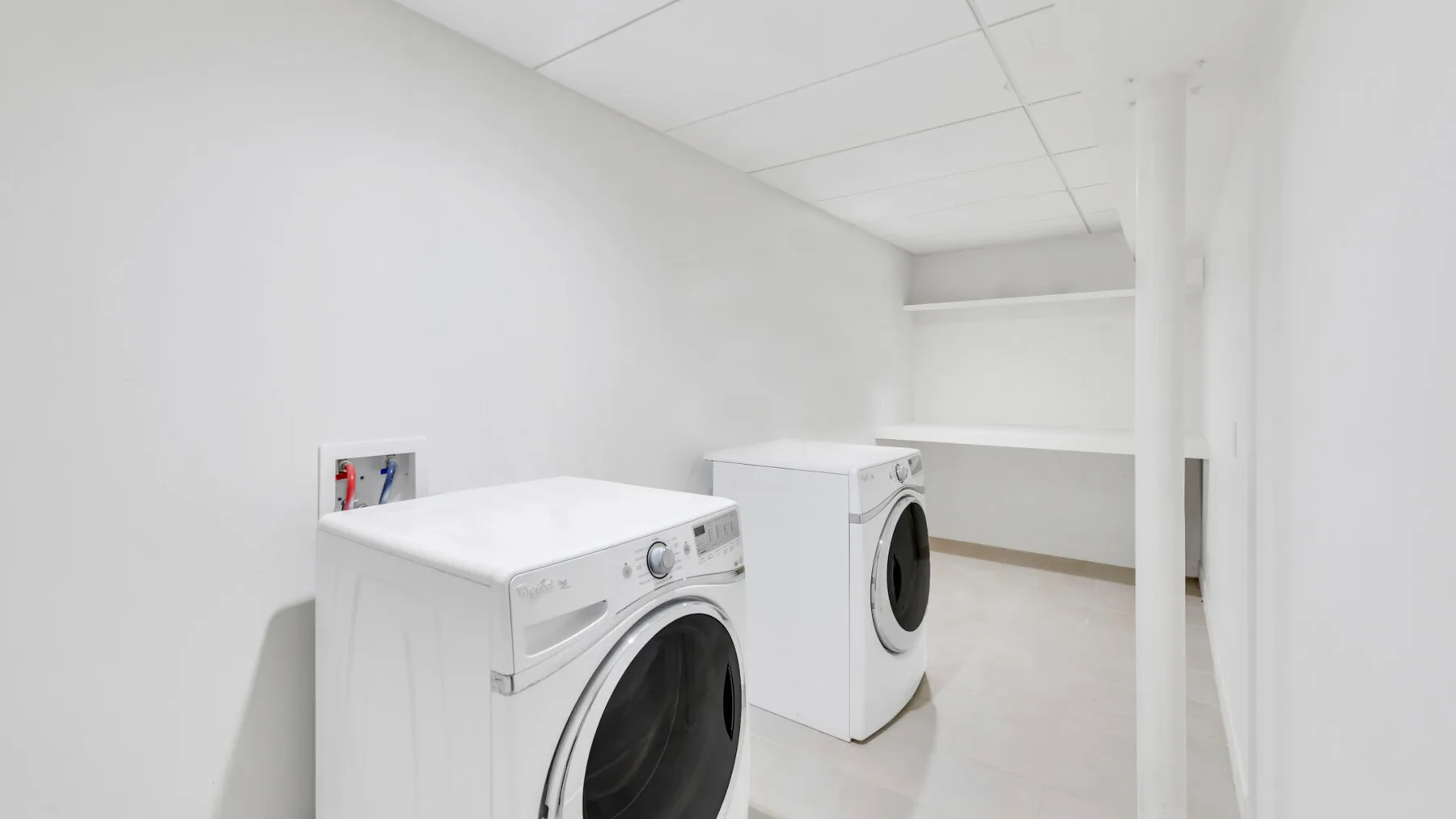 A laundry room with two white washing machines.