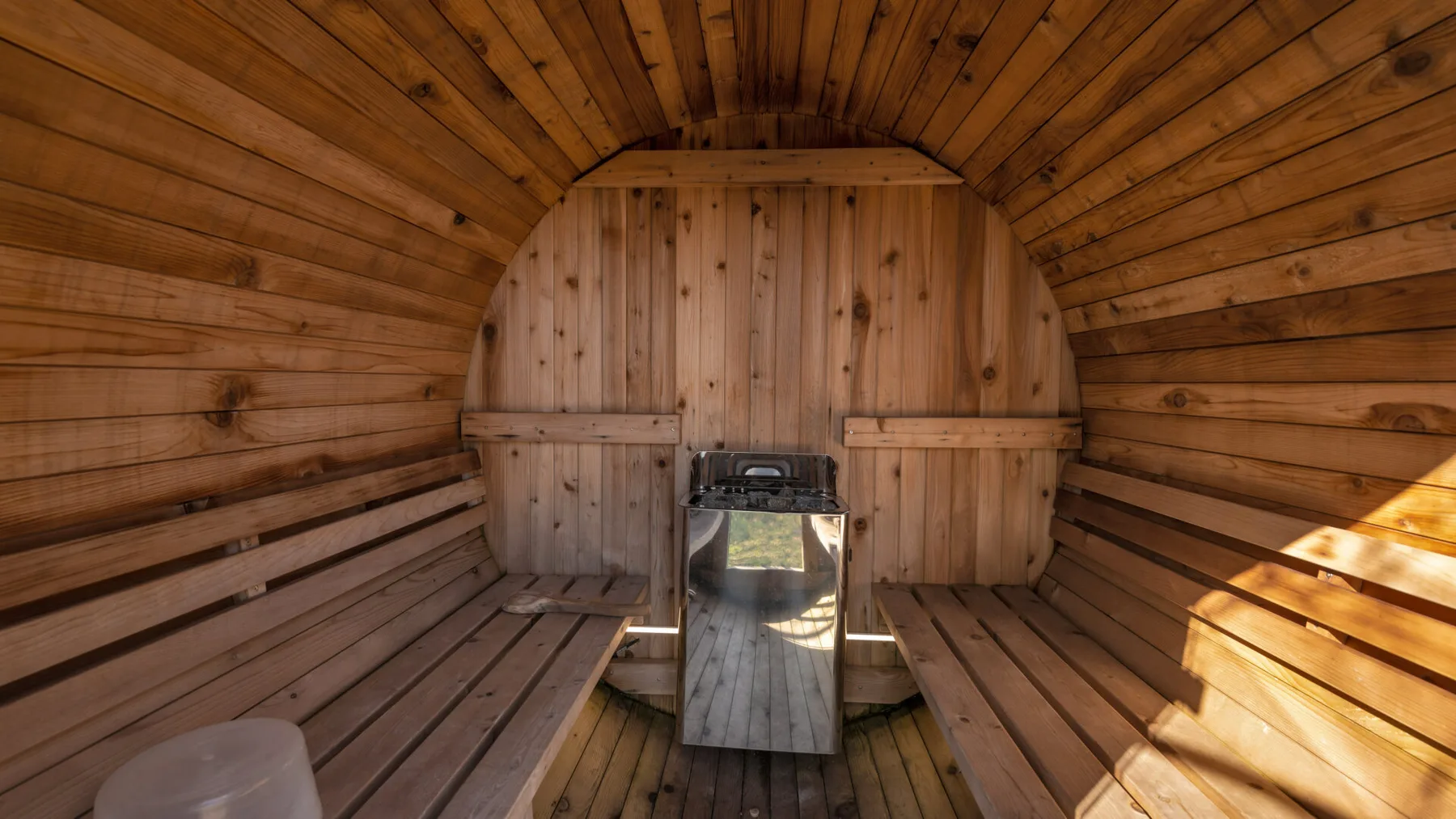 A wooden sauna room with built-in benches and a heater.