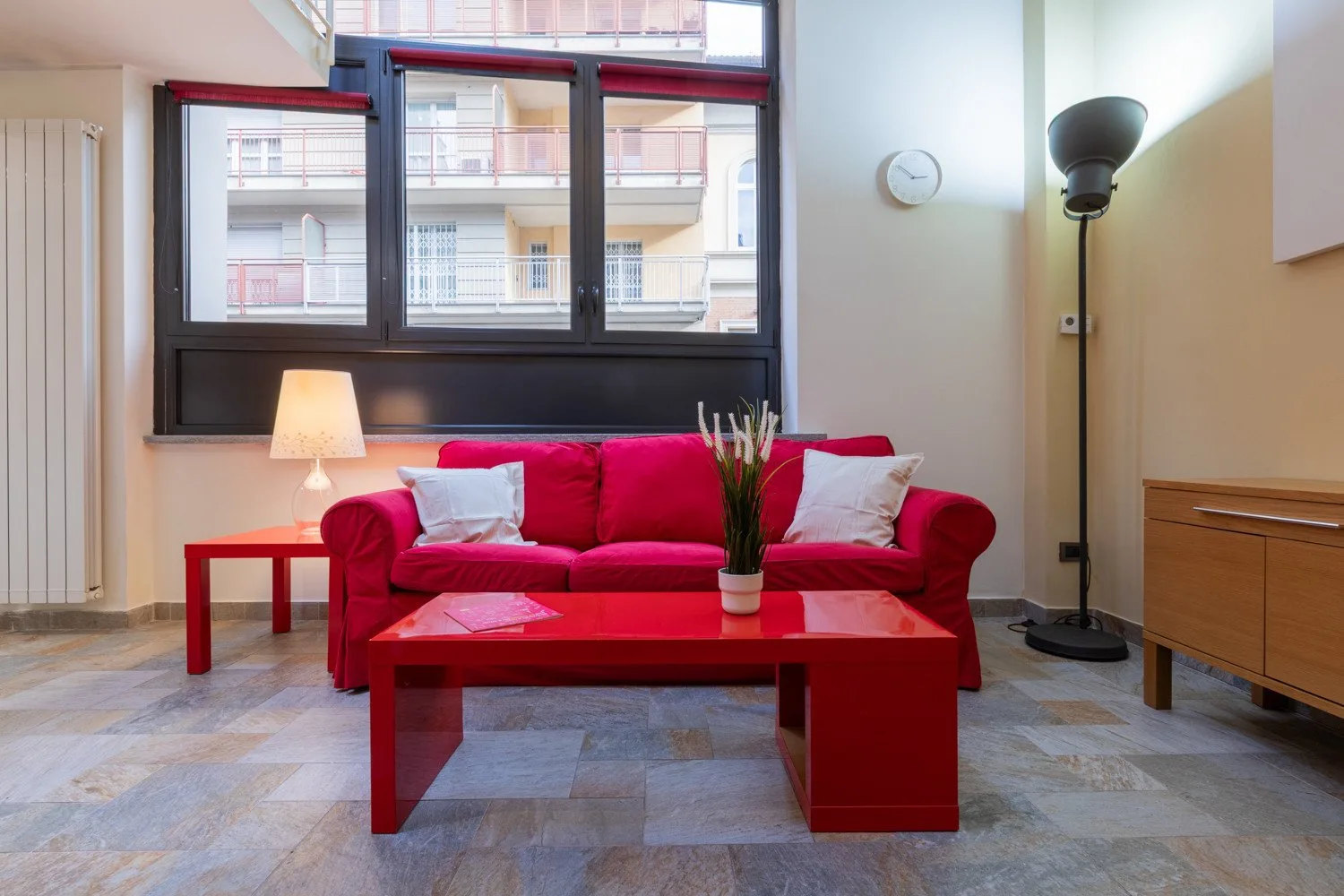 Una sala de estar con asientos rojos, una mesa baja y ventanas grandes.