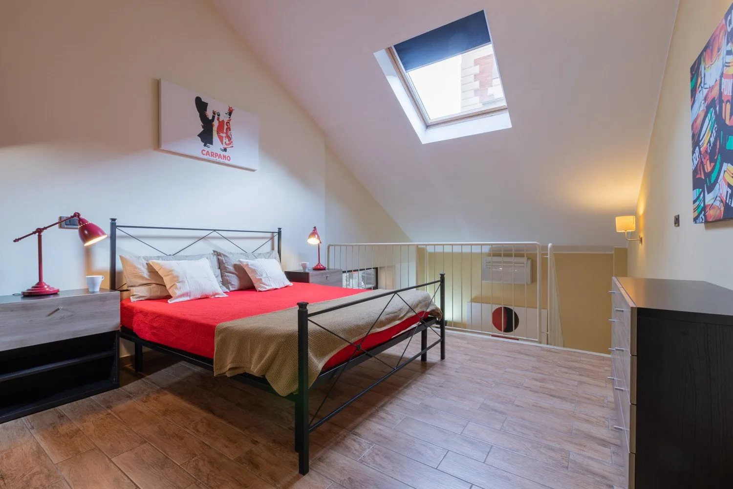 Un dormitorio con una cama roja, lámparas de noche y una claraboya.