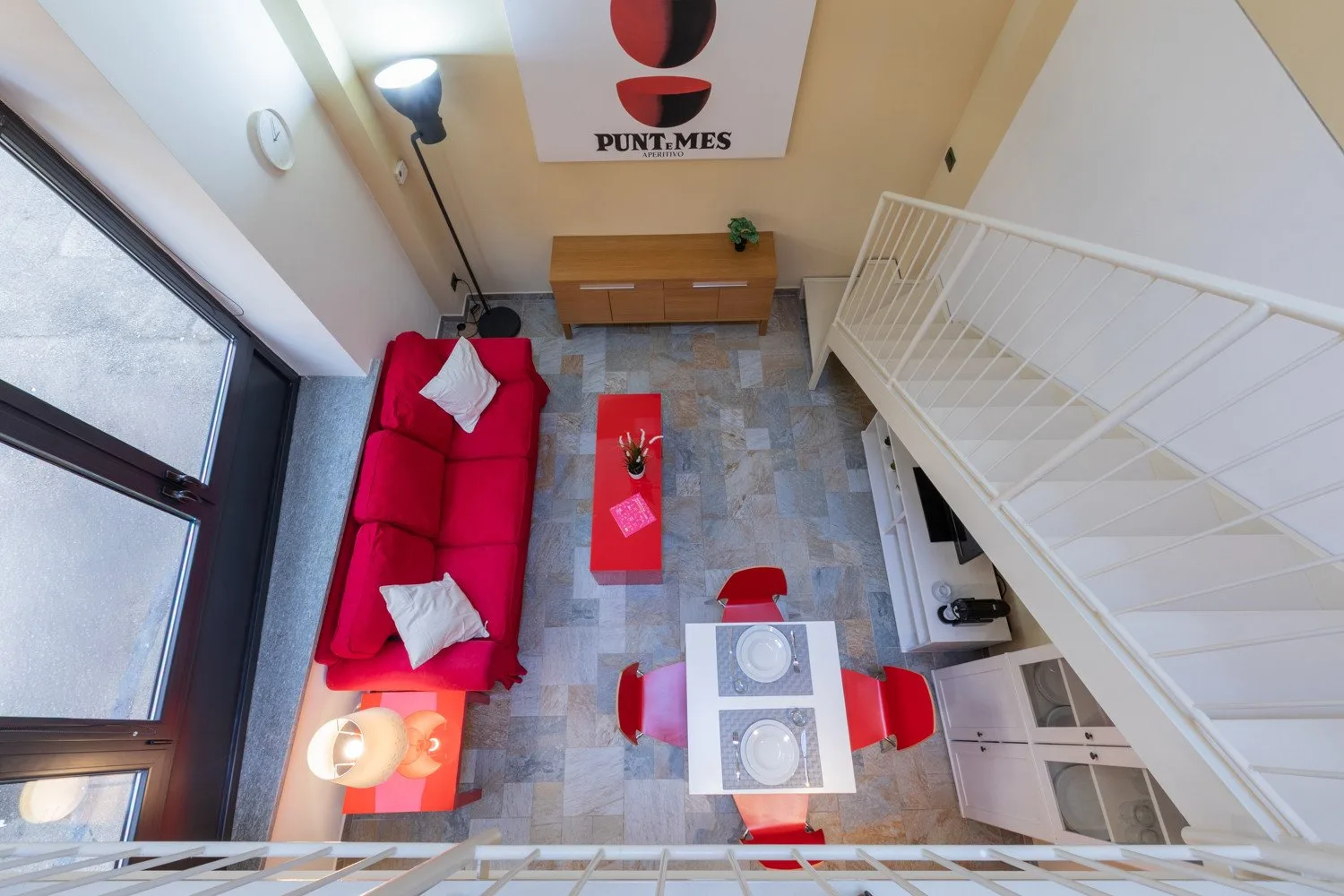 Una sala luminosa con asientos rojos, una mesa de centro y una escalera.