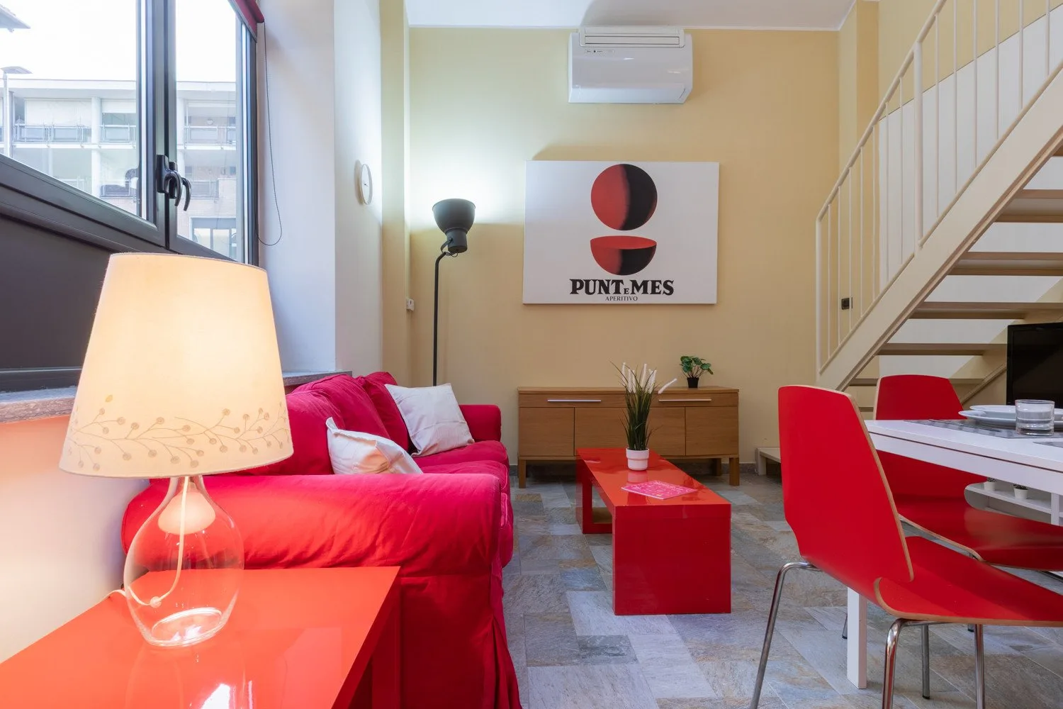 Zona de estar y comedor con asientos rojos y una mesa de centro.