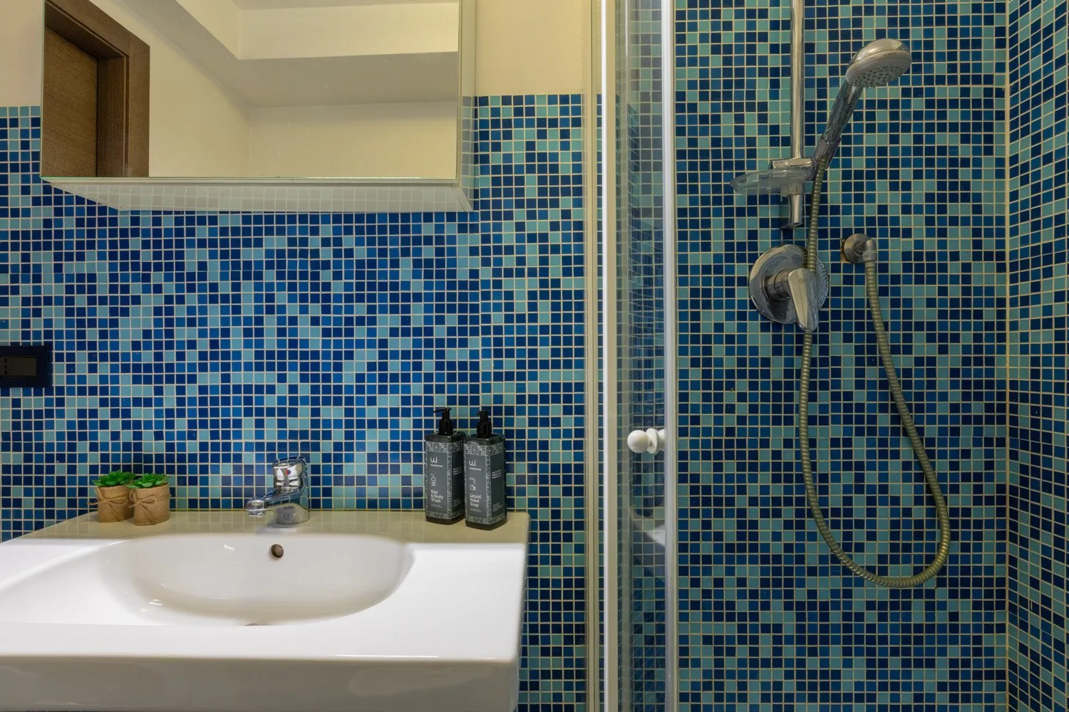 Un lavabo de baño junto a una ducha con azulejos.