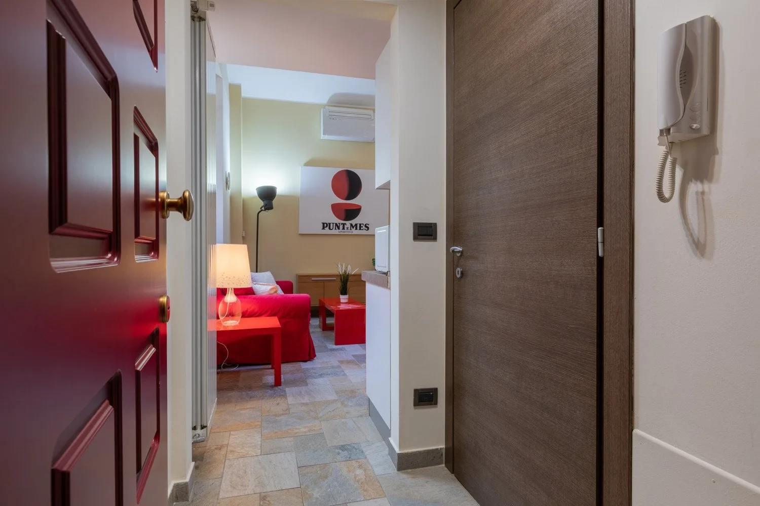 Un pasillo de entrada se abre a una sala de estar con asientos rojos.