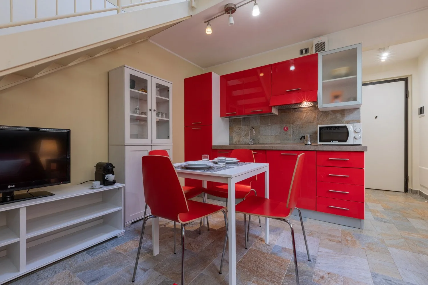 Una cocina compacta y zona de comedor con muebles rojos y una mesa.