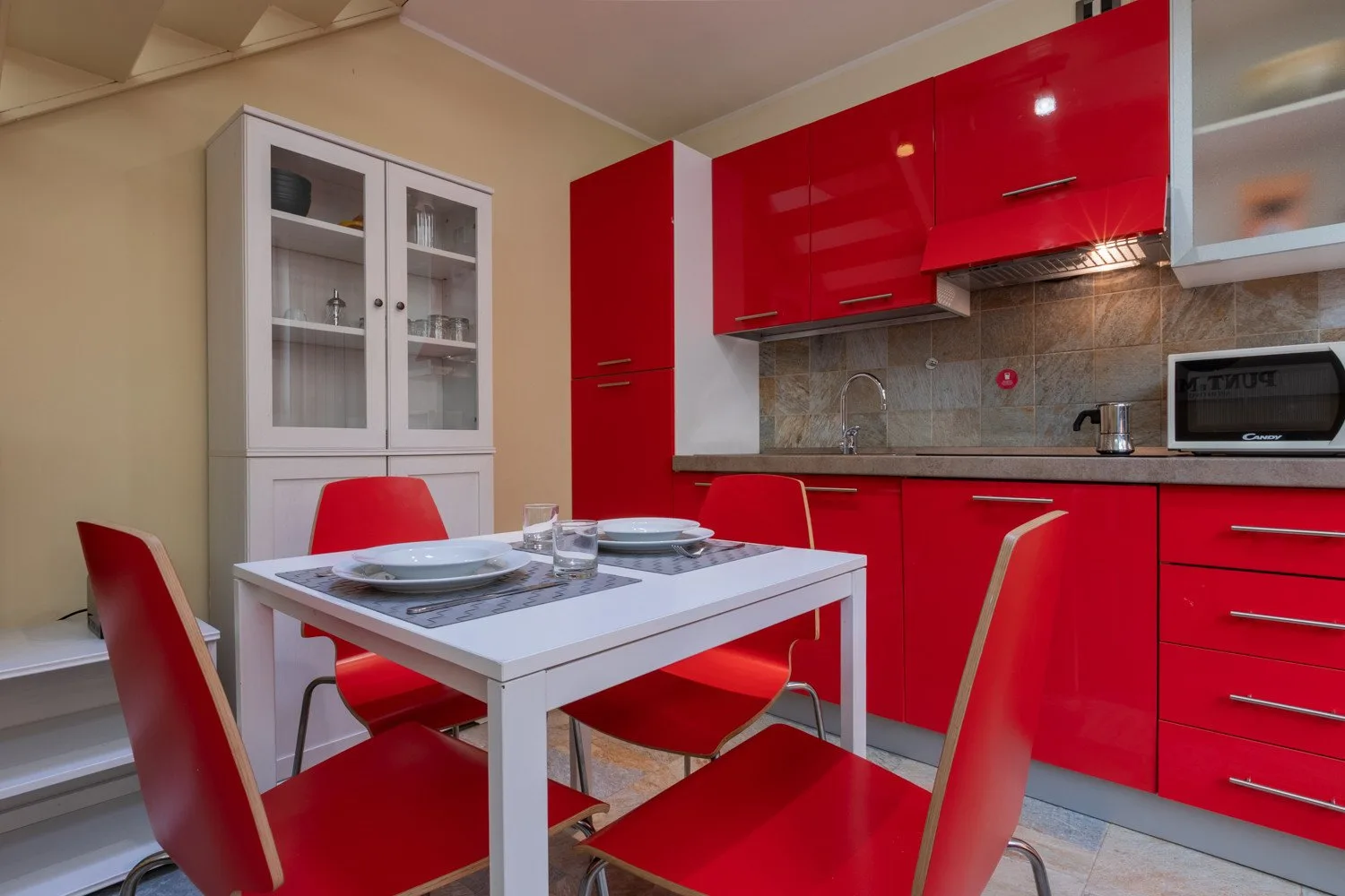Una cocina roja y blanca con una mesa de comedor y asientos rojos.