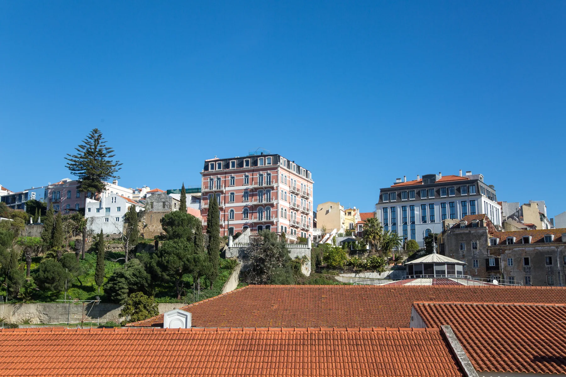 Un paisaje urbano en una ladera, con edificios coloridos sobre tejados de terracota.