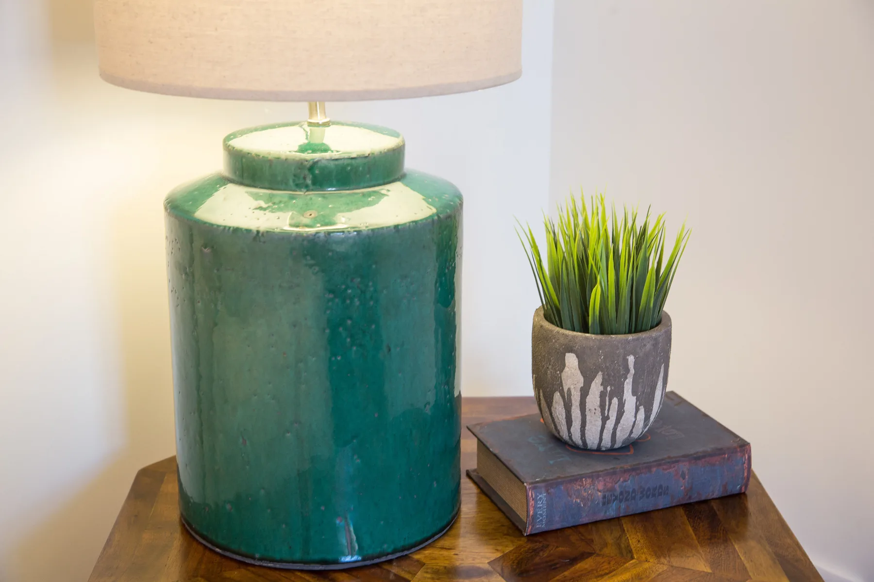 Una lámpara de mesa y una pequeña planta en maceta están sobre una mesa de madera.