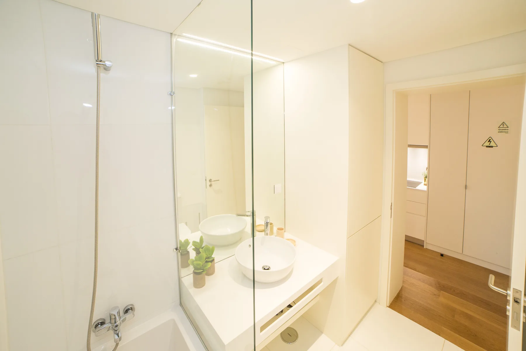 Un baño luminoso con ducha, lavabo y un espejo grande.