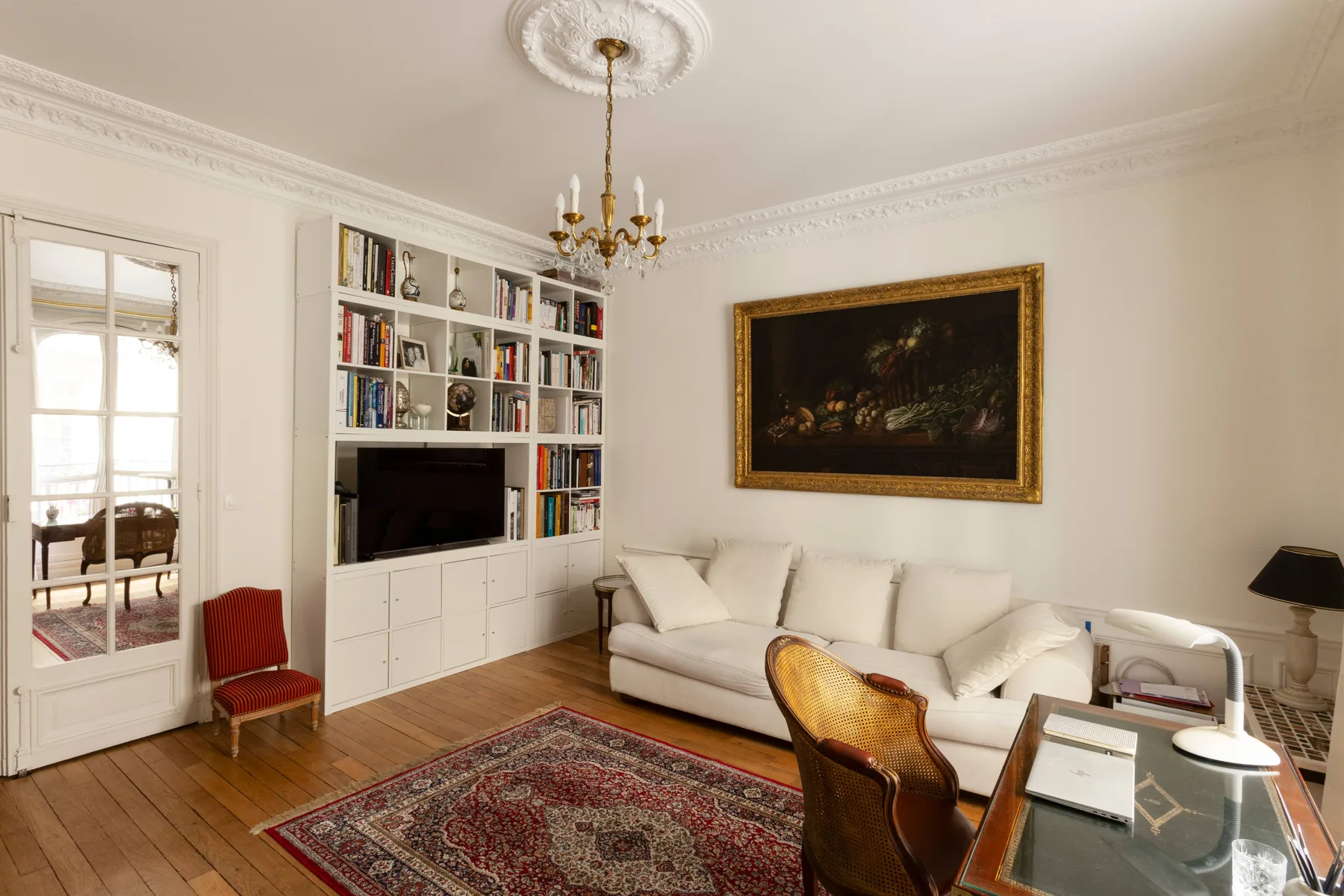 A living room with a white seating area, built-in bookshelves, and a patterned rug.