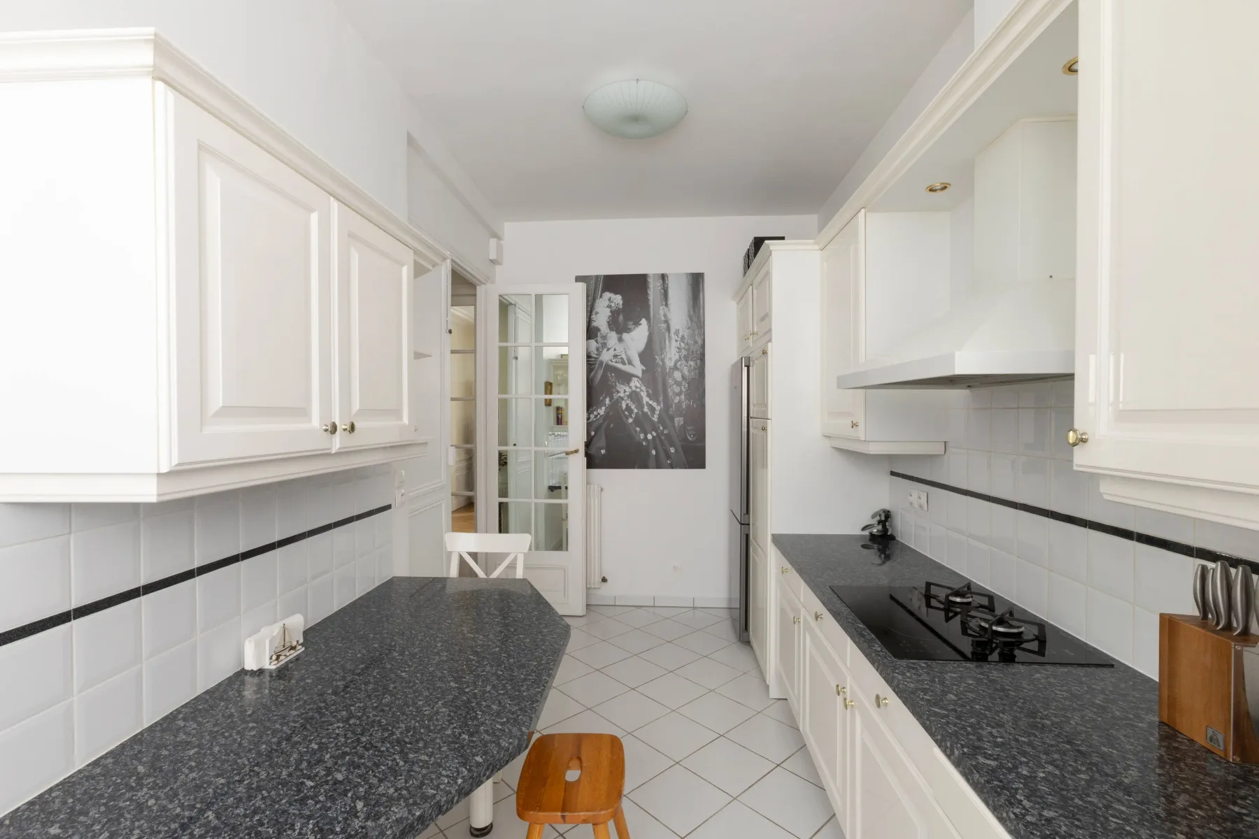 A bright kitchen with white cabinetry and dark countertops.