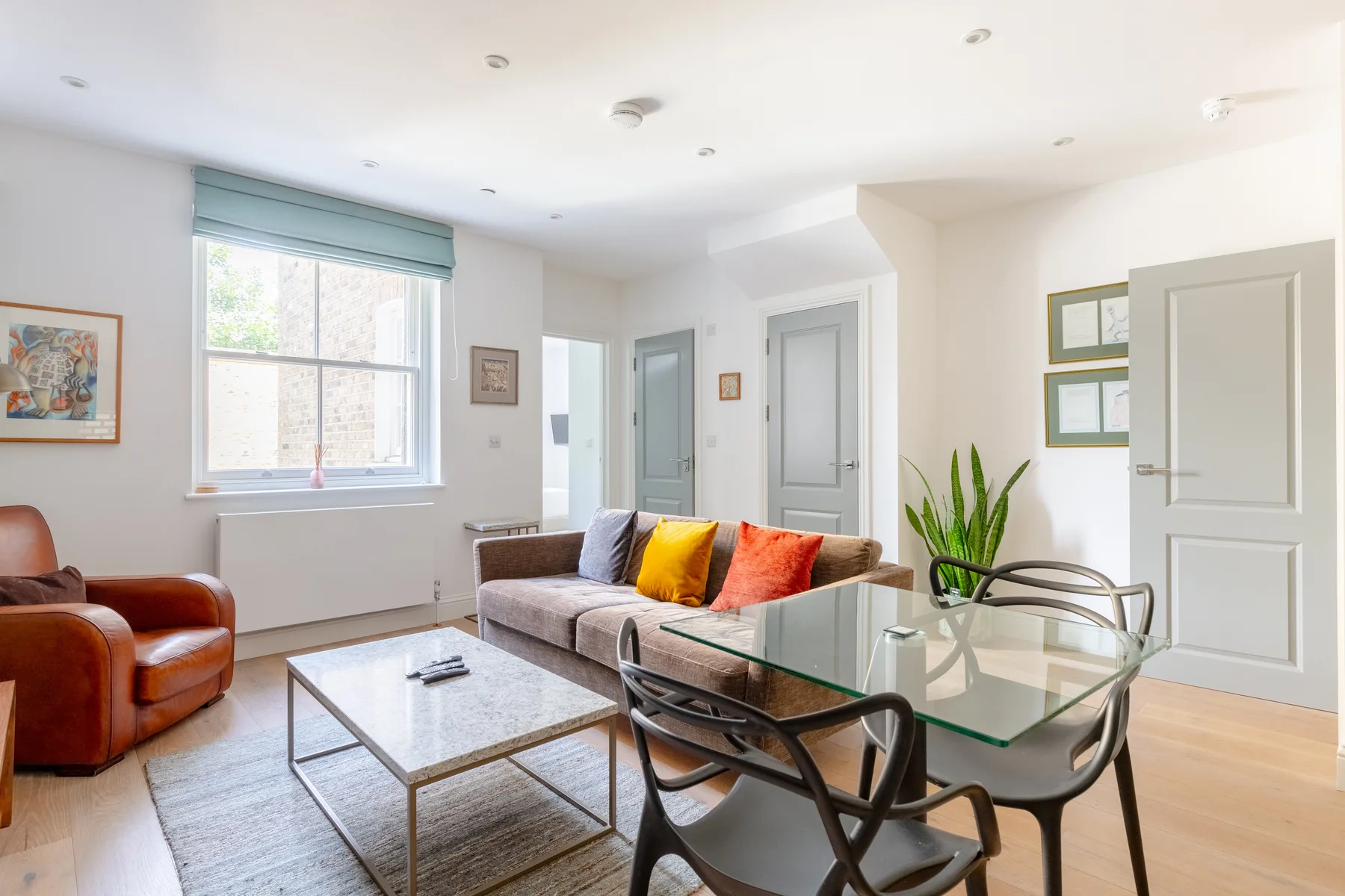 A bright living room with seating around a glass coffee table.