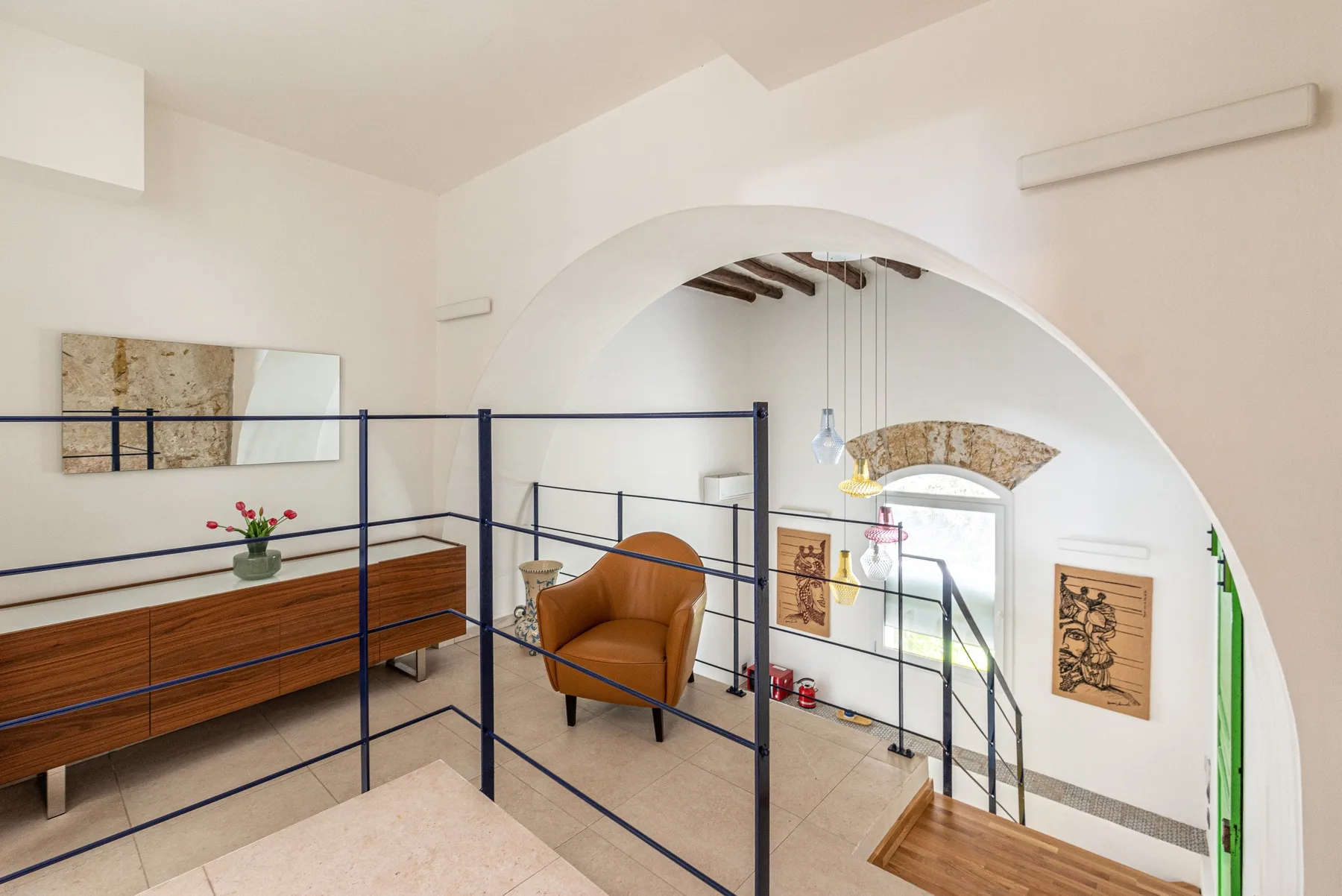 Una zona elevada con asientos da a una estancia inferior a través de un gran arco.