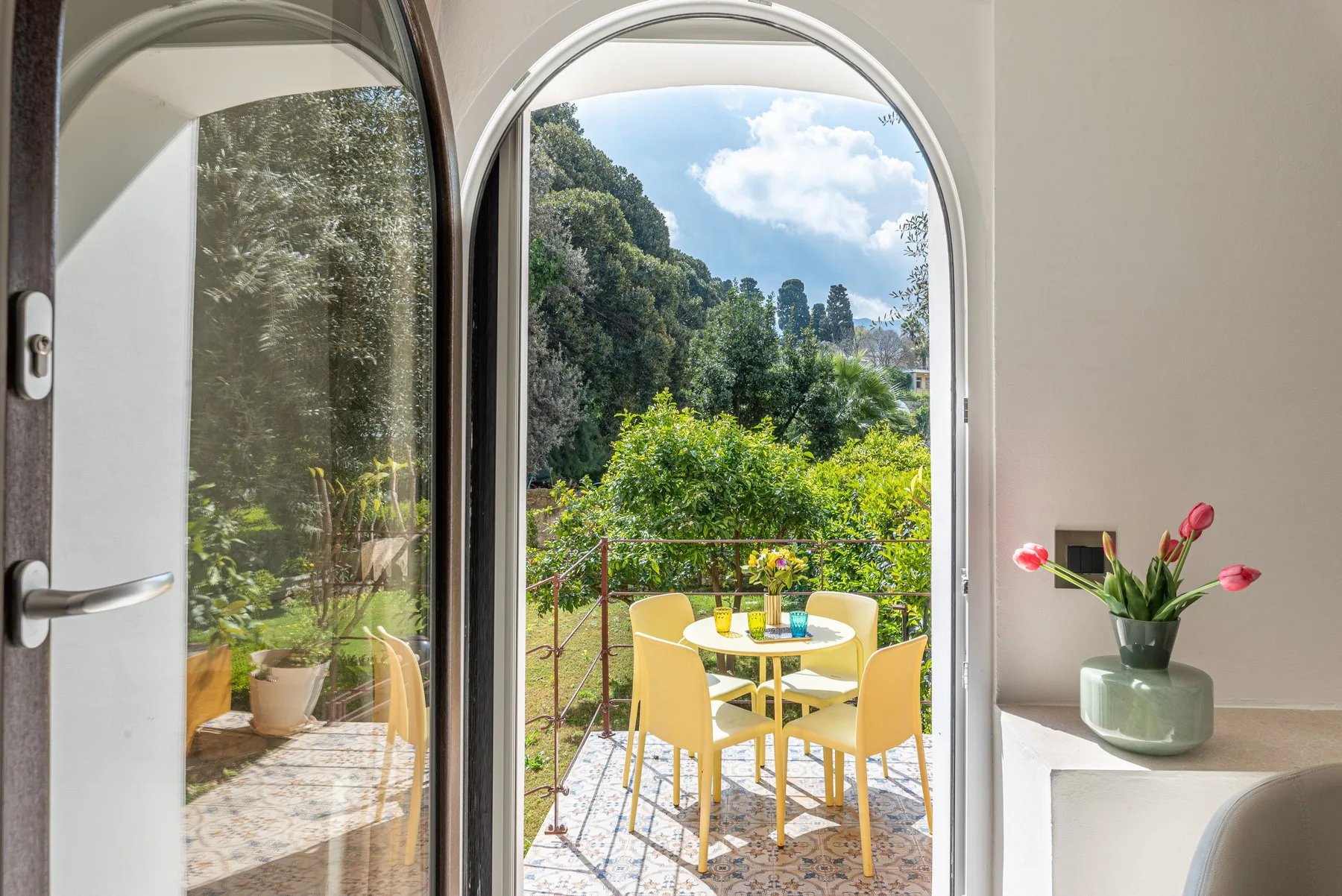 Una puerta arqueada da a un patio con una mesa pequeña y sillas.