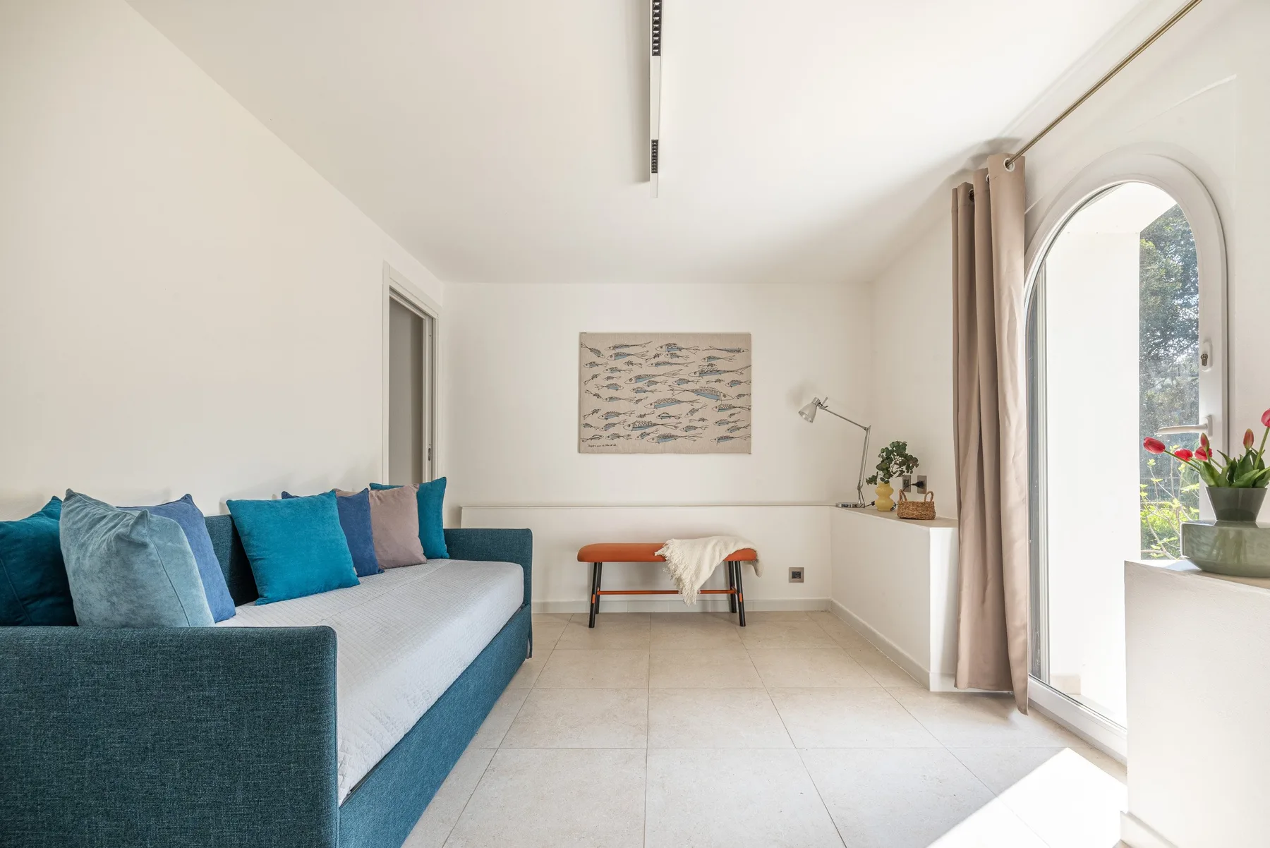 A bright living room with a blue sectional and a small seating area.