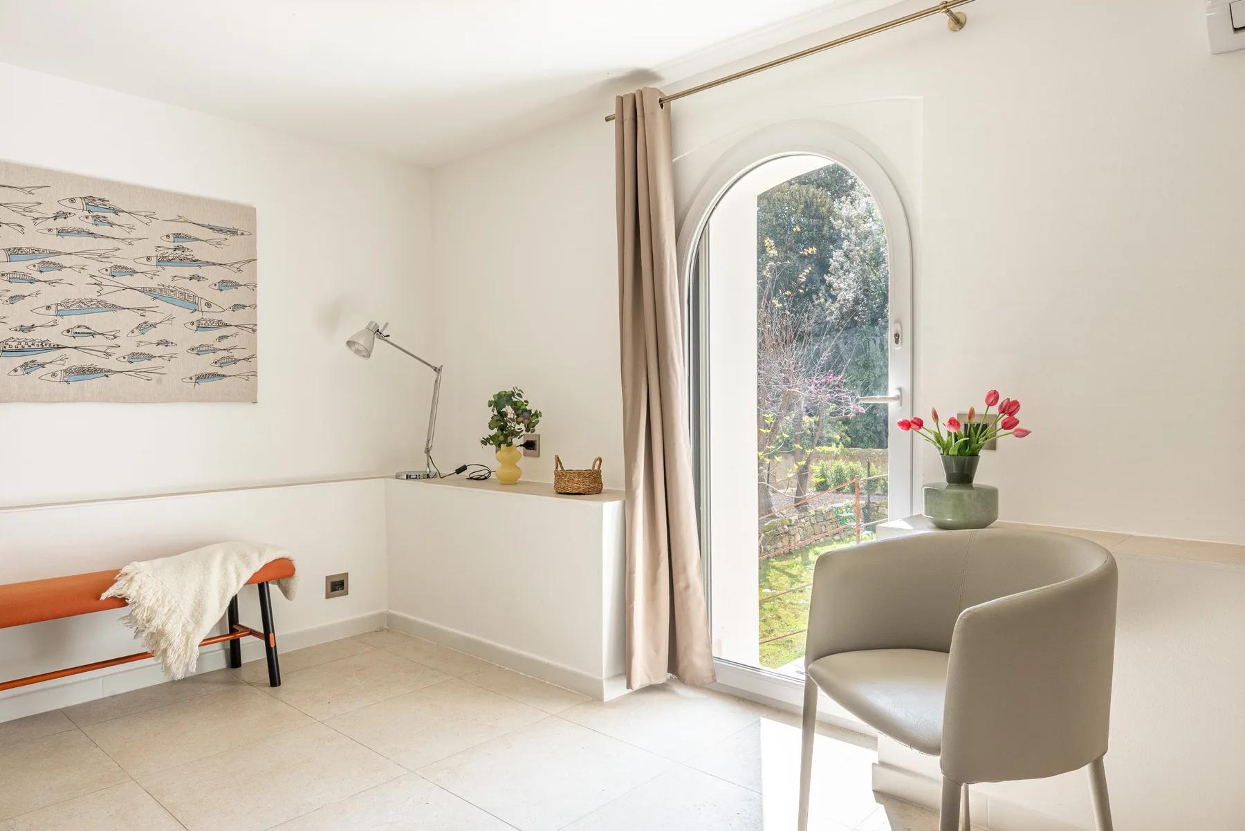Una luminosa zona de estar con puerta acristalada arqueada y un asiento acolchado.