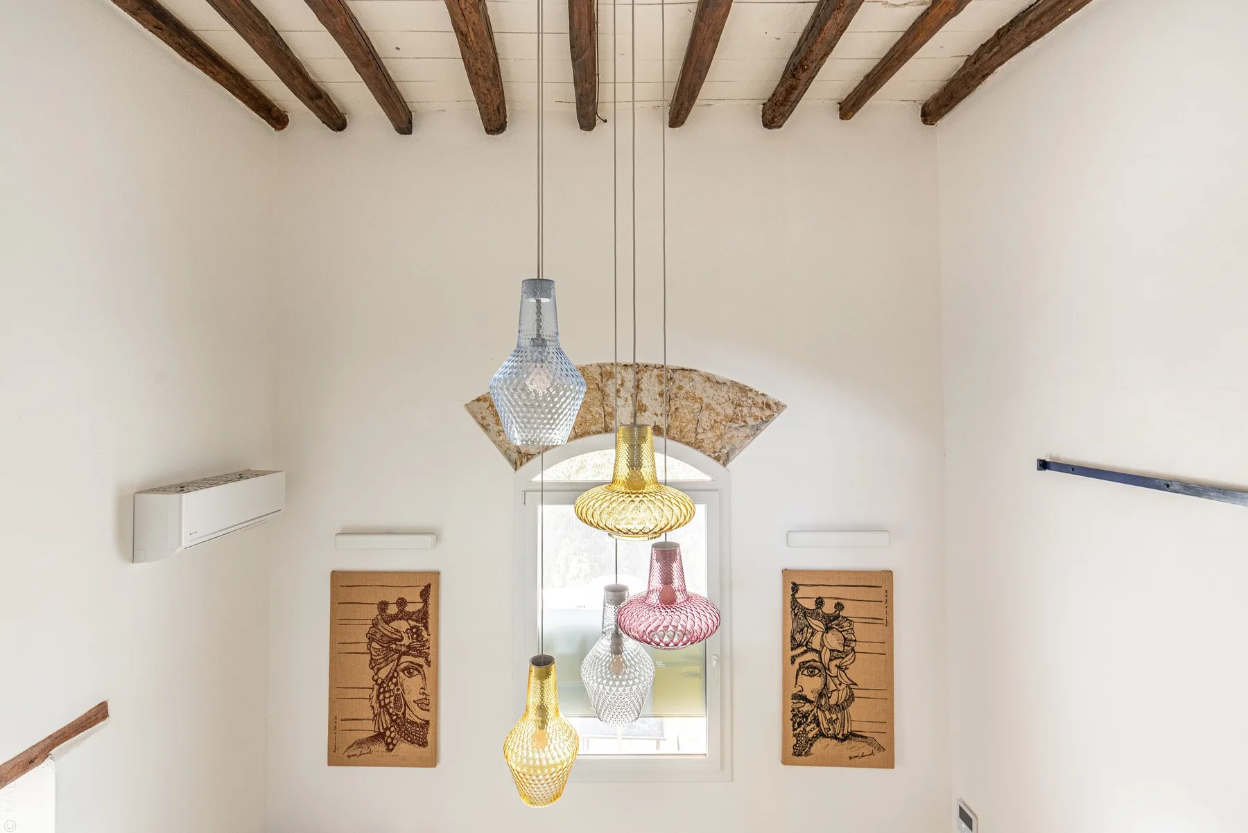 Una habitación luminosa con vigas de madera expuestas y lámparas colgantes.