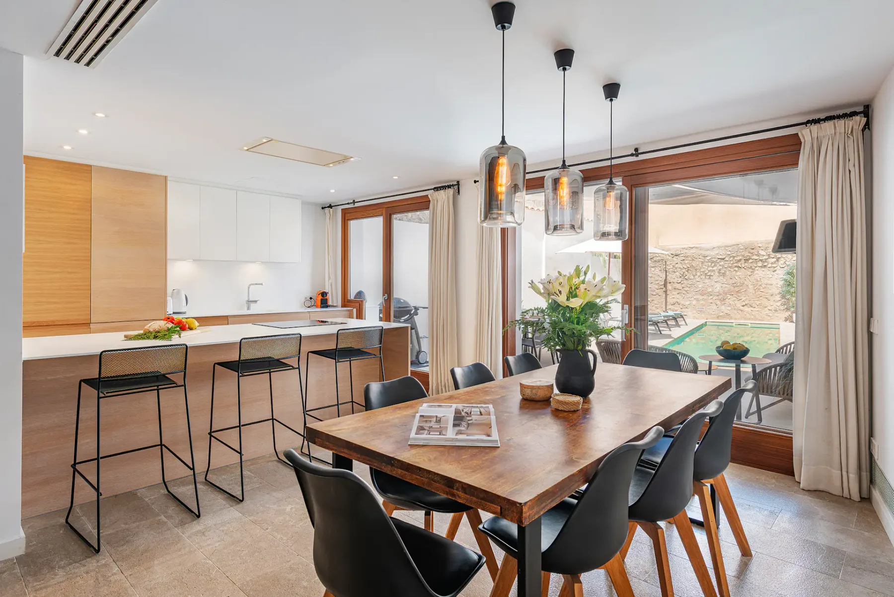 An open-plan dining and kitchen area has a wooden table and a counter with bar seating.