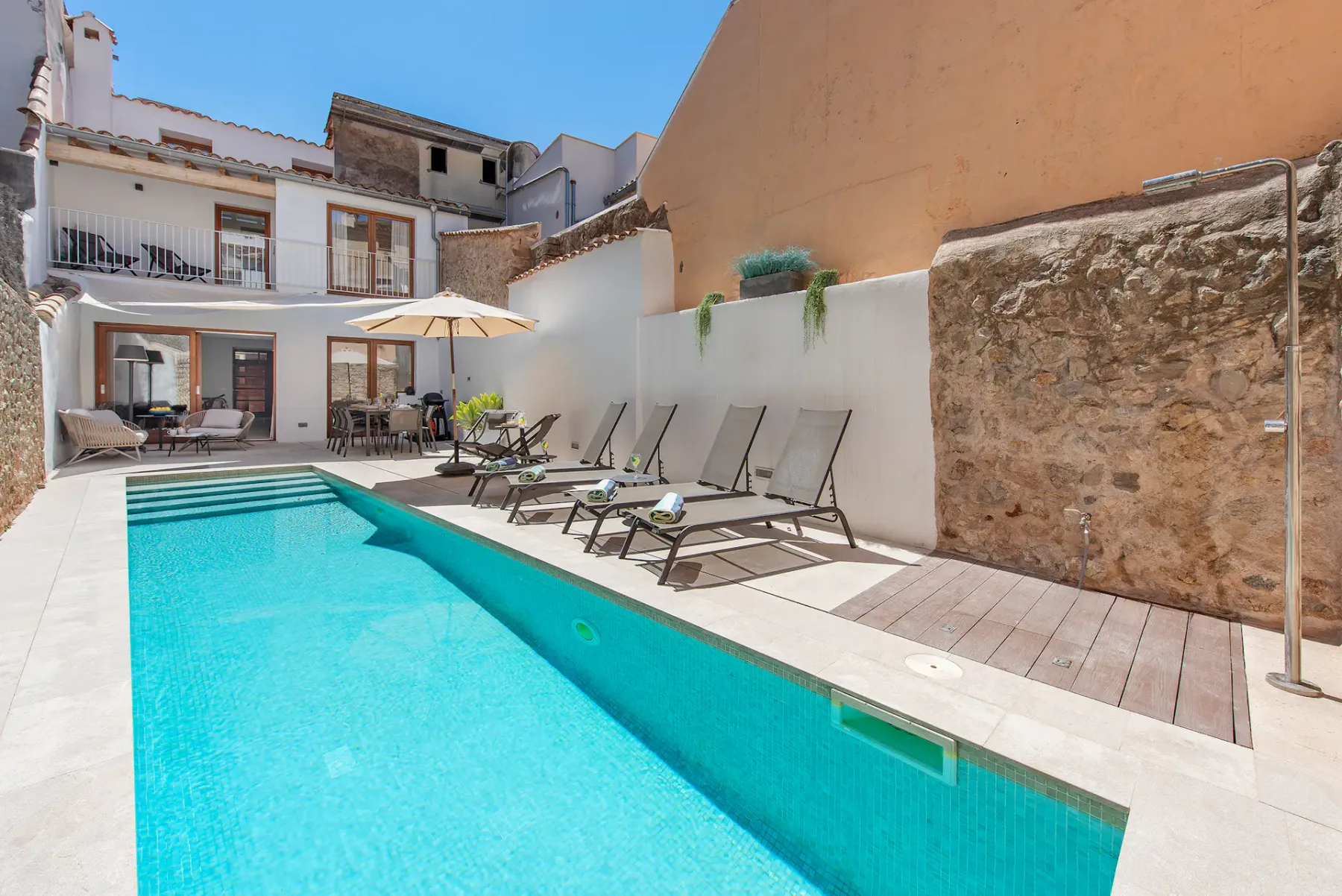 A courtyard swimming pool is lined with lounge chairs and a shaded seating area.