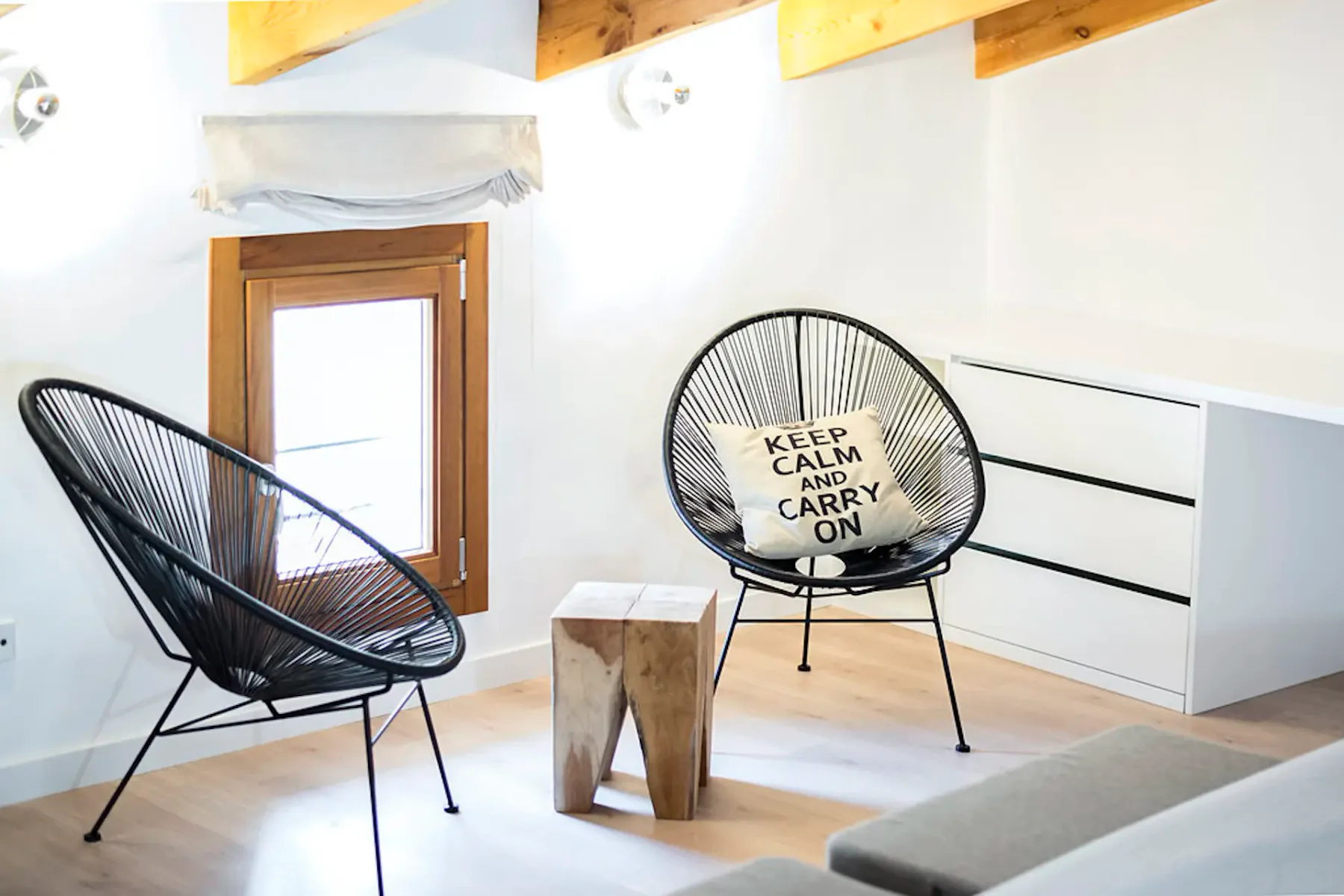 A bright sitting area with two wire chairs, a small table, and a low cabinet.