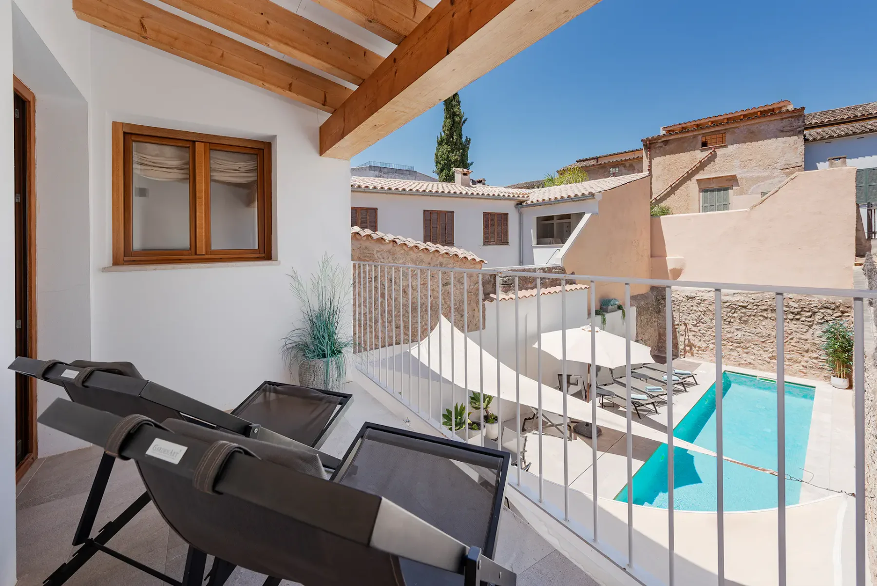 A sunlit terrace with reclining seating overlooks a small swimming pool.