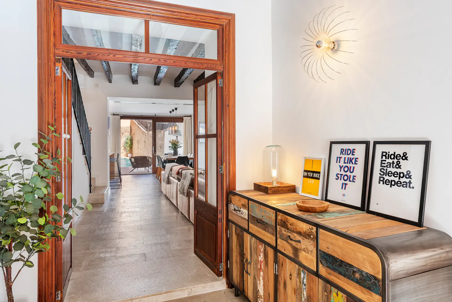 A bright interior hallway opens into a living area, with a wooden console along the wall.