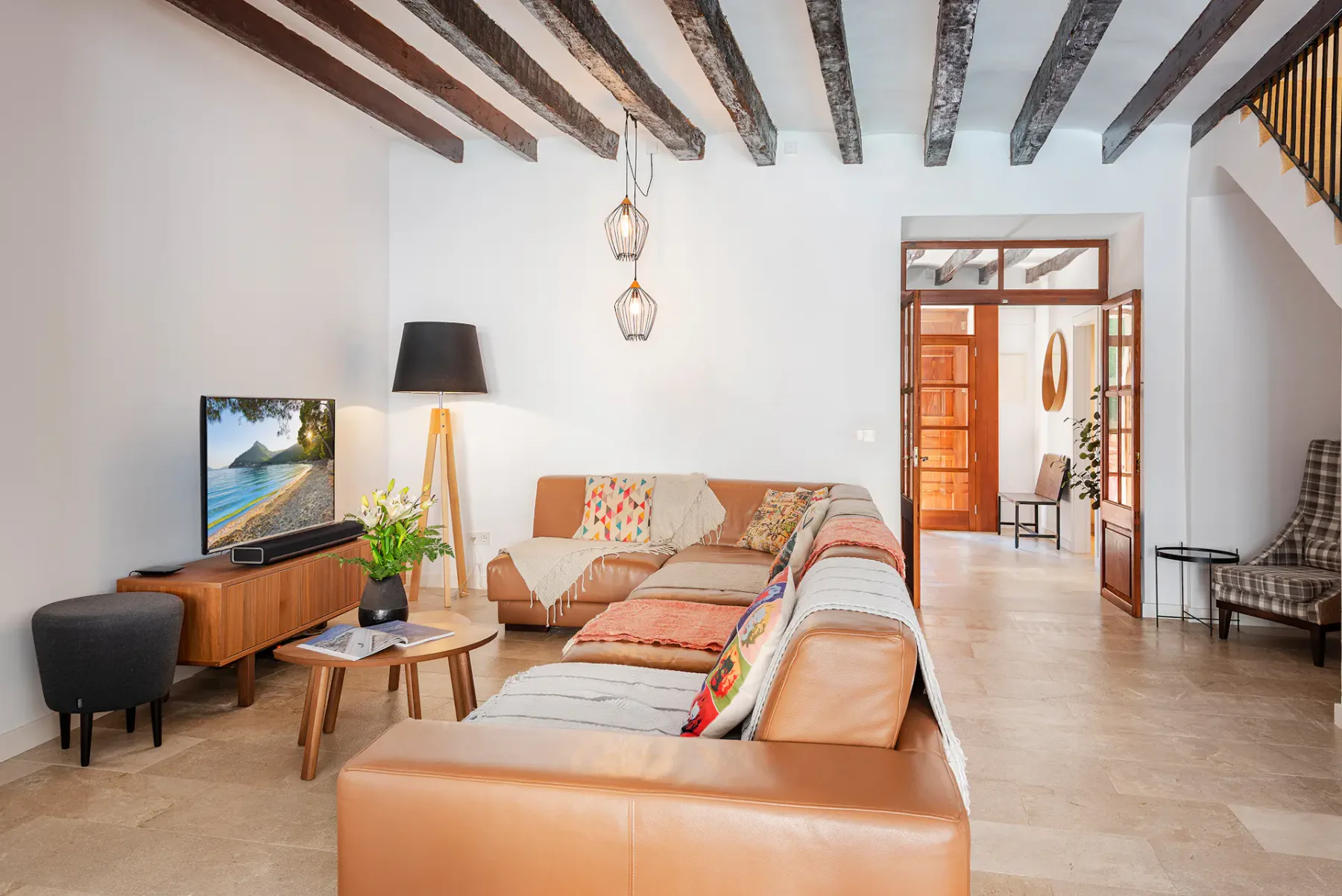 A living room with seating, a television, and exposed ceiling beams.